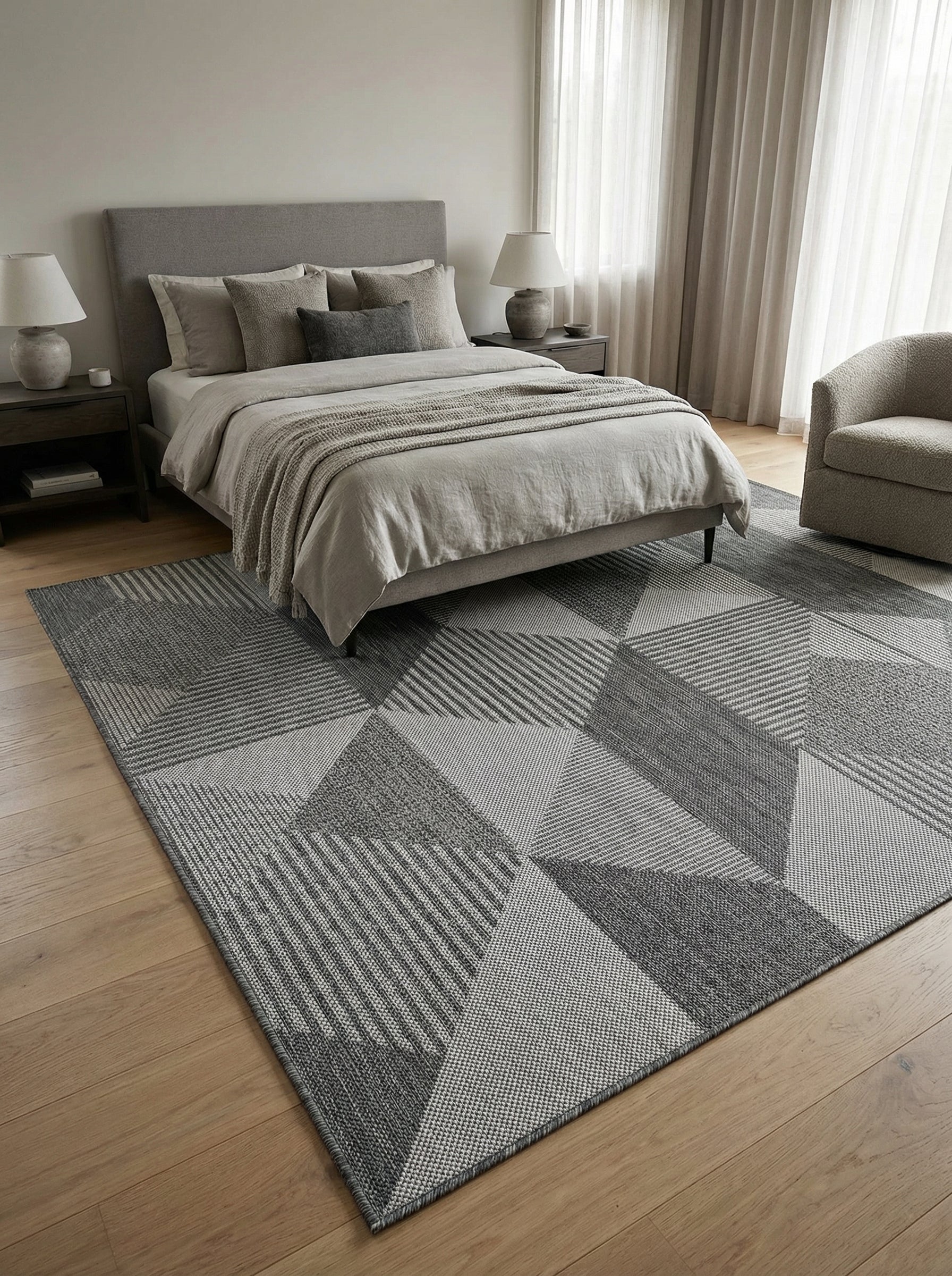 Tapis rectangulaire gris aux motifs géométriques de triangles, avec des textures et des rayures variées, dans une chambre