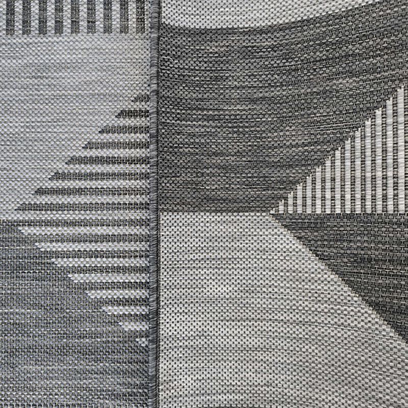 Tapis tissé à plat avec des motifs géométriques abstraits en nuances de gris clair et foncé