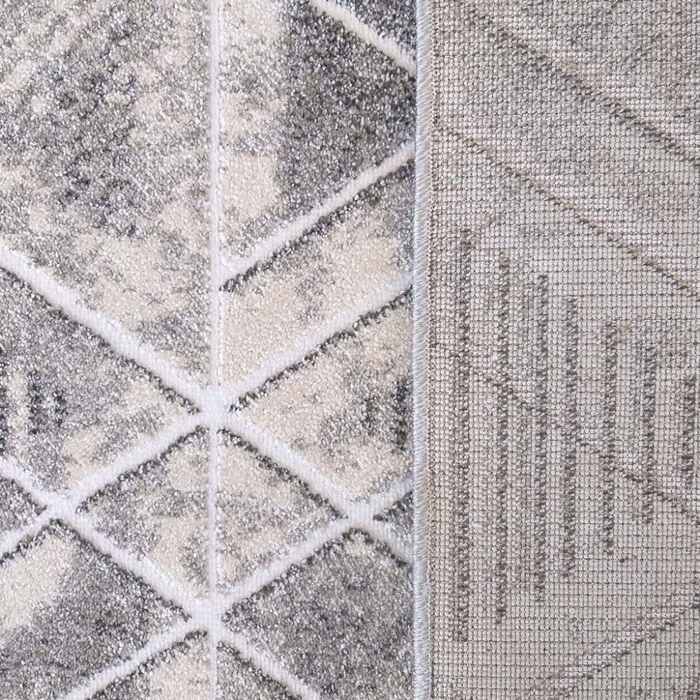 Tapis à poils courts avec motifs géométriques abstraits en gris, crème et blanc, et son envers tissé apparent