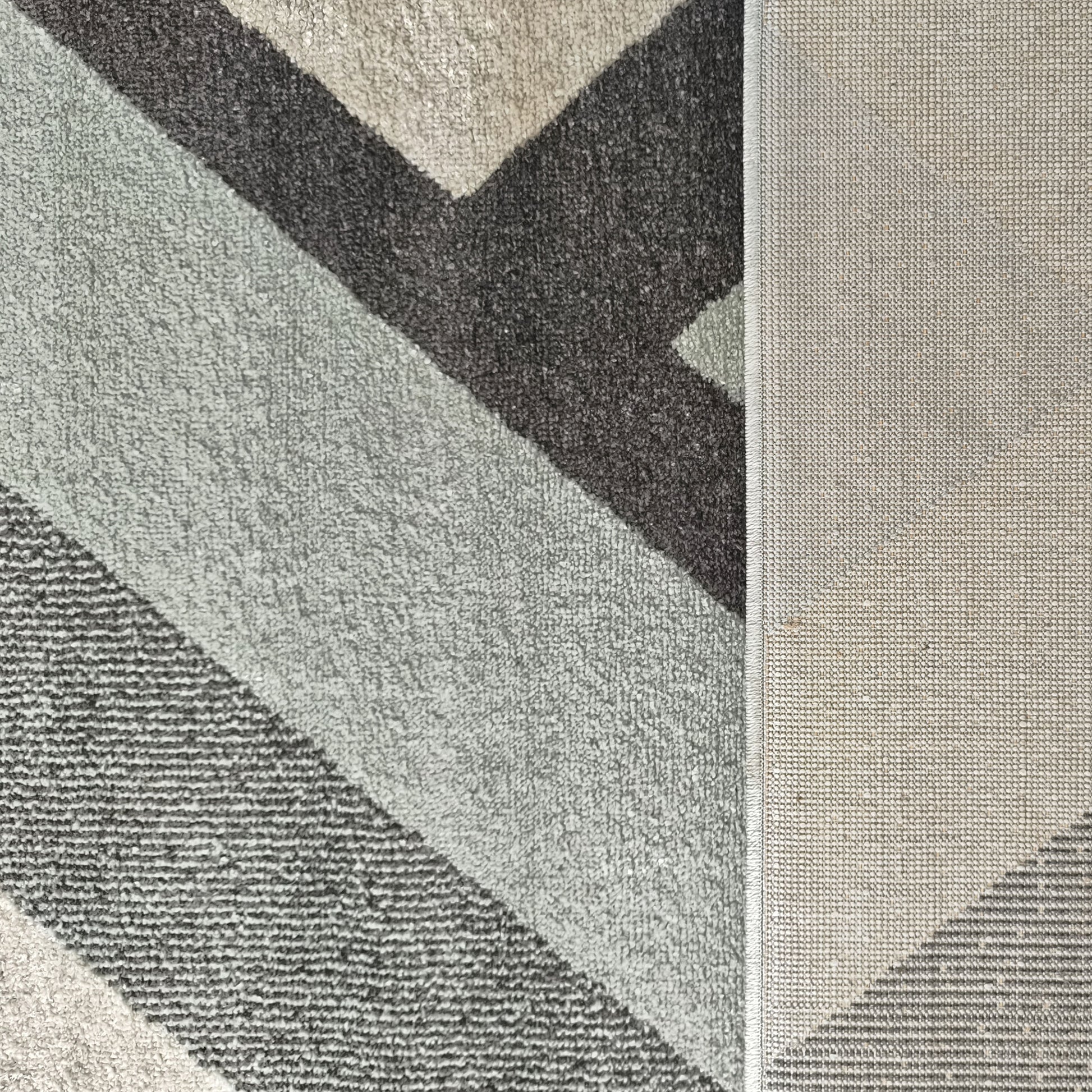 Tapis aux motifs géométriques diagonaux gris foncé, gris clair et vert menthe, montrant une texture de boucles et son envers tissé
