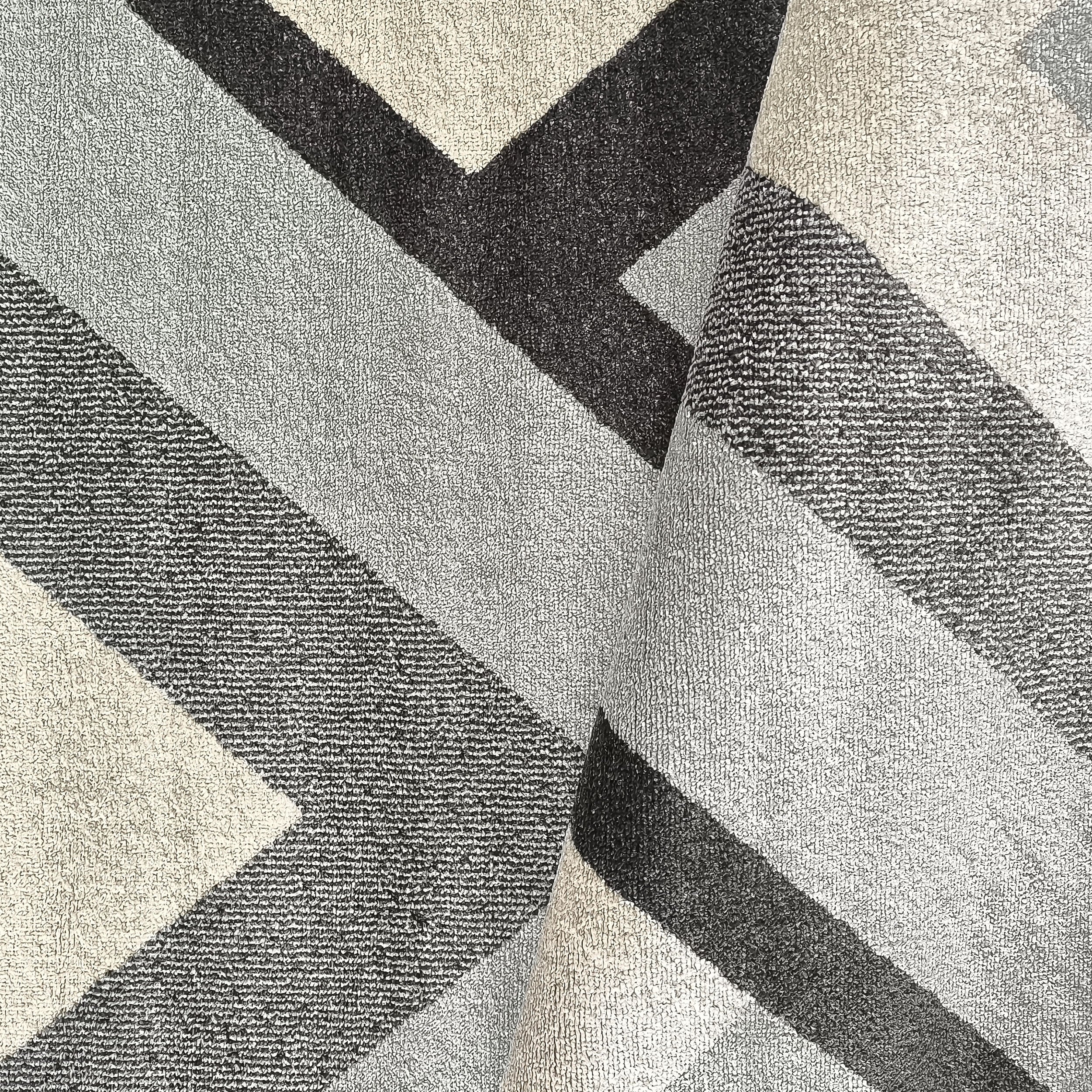 Tapis à motifs géométriques en zigzag de tons gris, anthracite et beige clair, avec une surface textile moelleuse