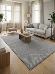 Tapis rectangulaire gris et blanc aux motifs tissés en bandes alternant chevrons, lignes et formes géométriques, dans un salon lumineux