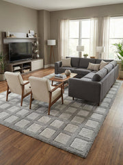Tapis rectangulaire shaggy bicolore, gris pour le quadrillage et crème pour les carrés, au sol d'un salon moderne