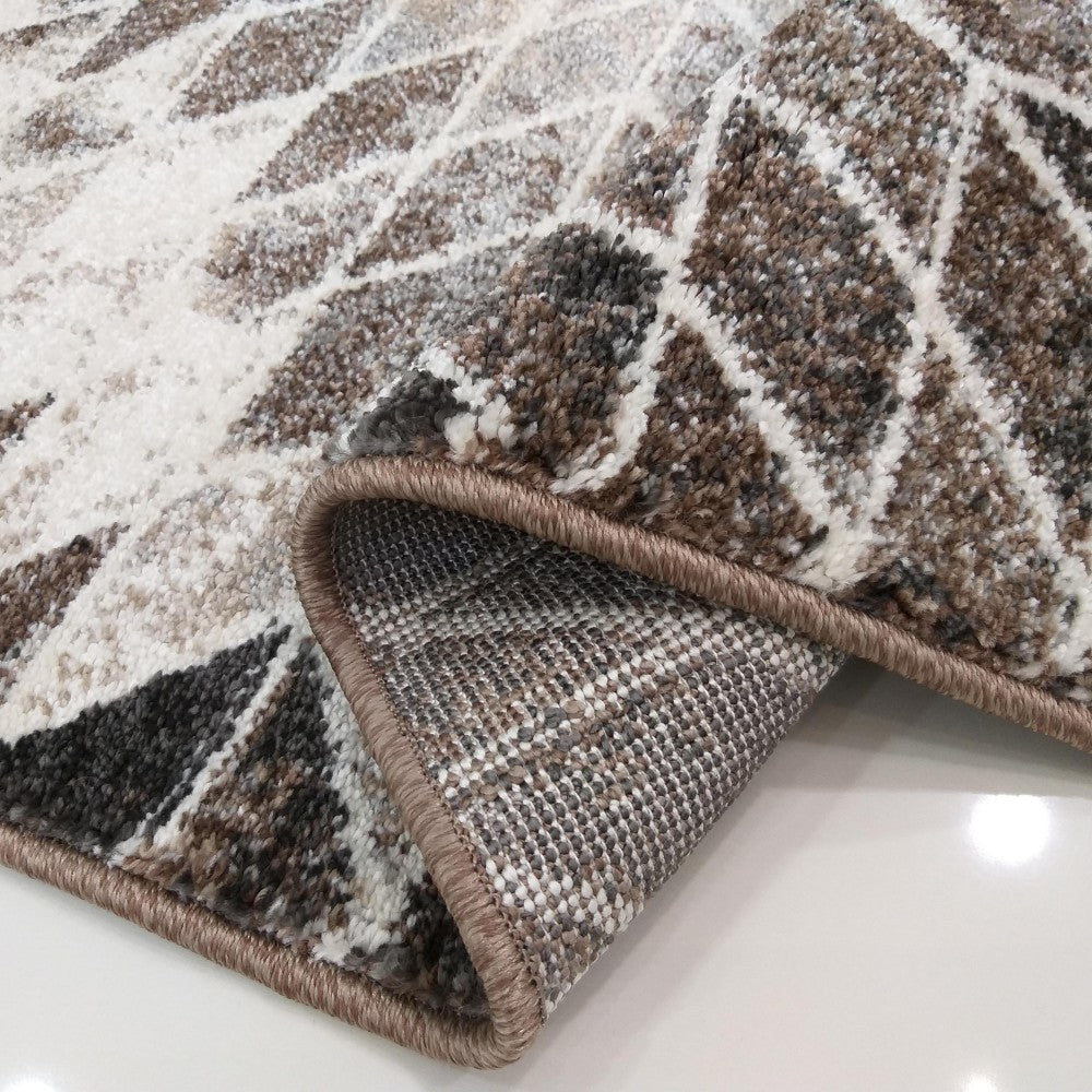 Tapis moelleux aux motifs géométriques marron, blanc et gris, montrant son envers tissé et sa bordure beige