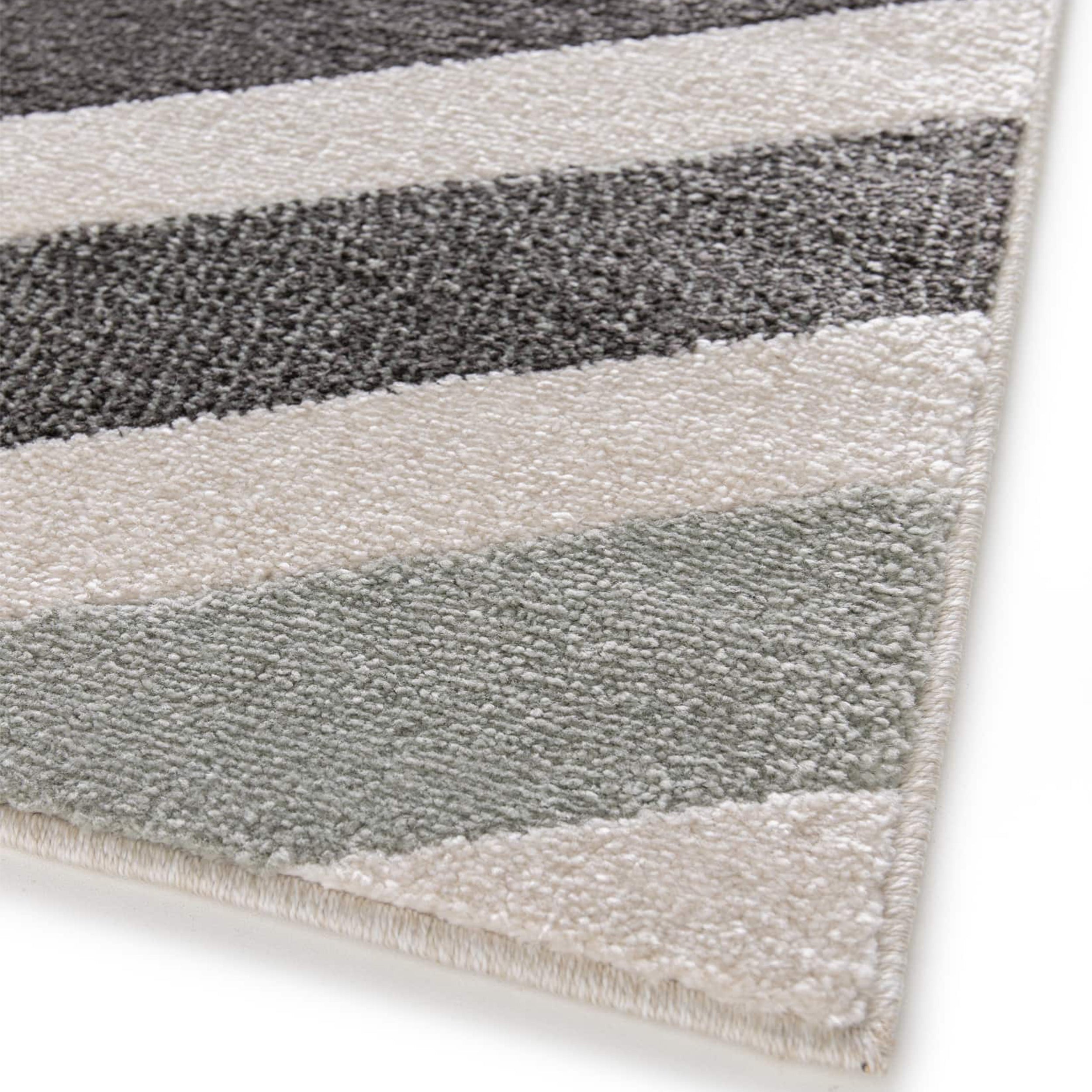 Tapis à texture douce, affichant des rayures diagonales en gris anthracite, blanc crème et gris-vert pastel
