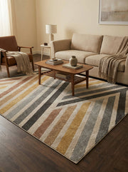 Tapis rectangulaire à poils texturés, motifs de larges rayures diagonales beige, gris, noir, ocre et rouille, dans un salon moderne