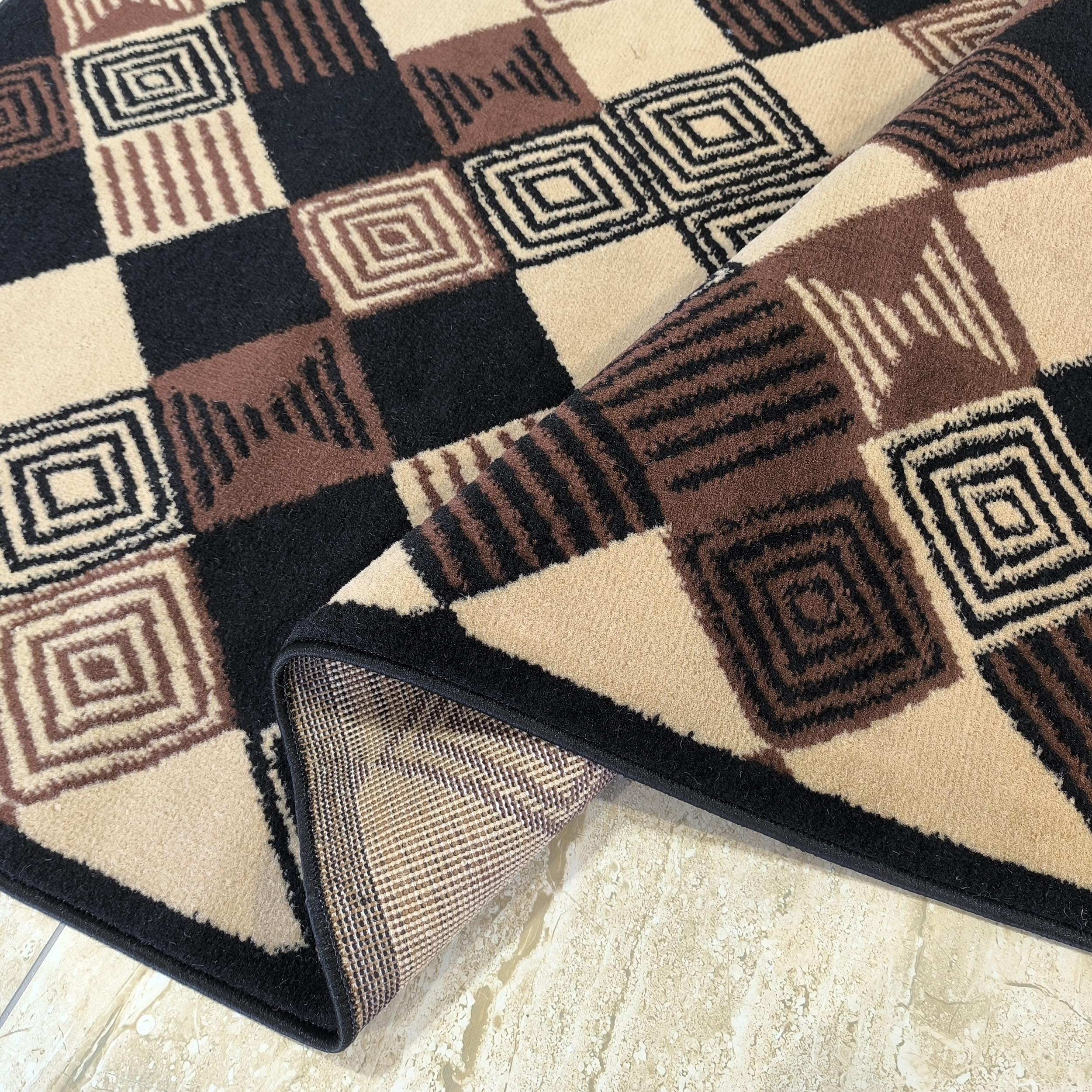 Tapis enroulé avec des motifs géométriques de carrés beiges, marrons et noirs, certains à rayures ou concentriques