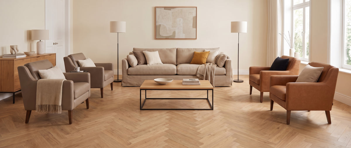 Ambiance sobre et chaleureuse dans un salon sans tapis, au parquet chevrons clair, avec canapé et fauteuils