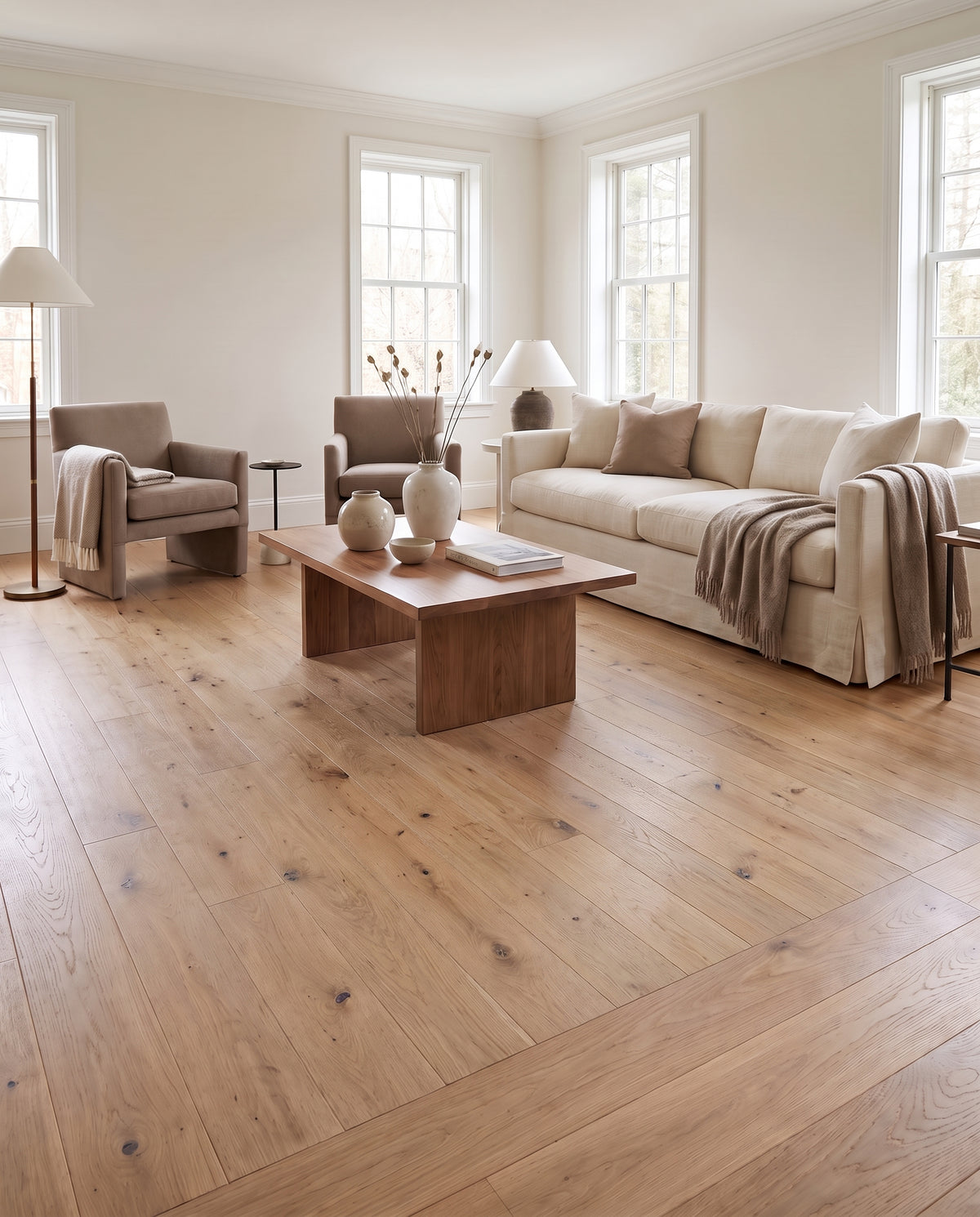 Un salon lumineux et épuré aux tons neutres, avec un sol en parquet de bois clair sans tapis apparent