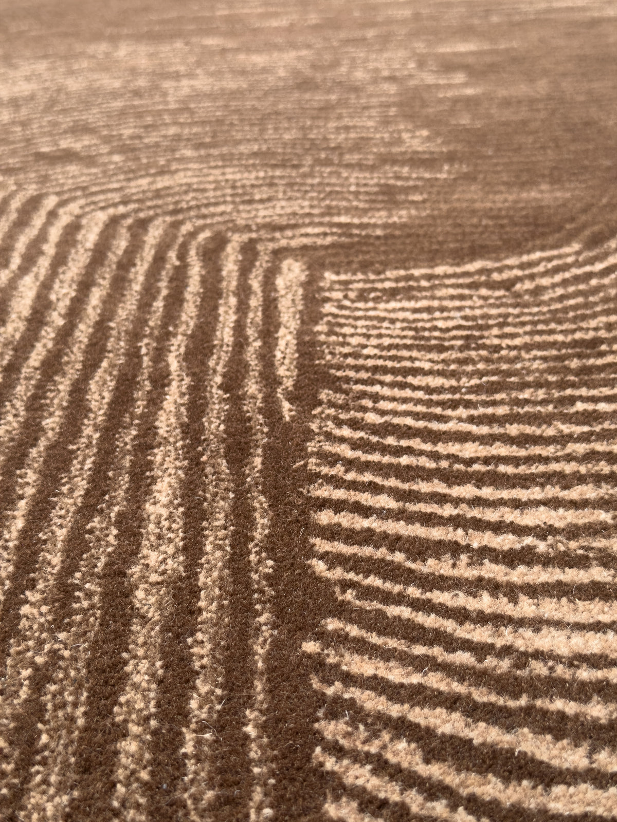 Relief texturé d'un tapis laine et coton, ses vagues alternent brun chocolat et beige