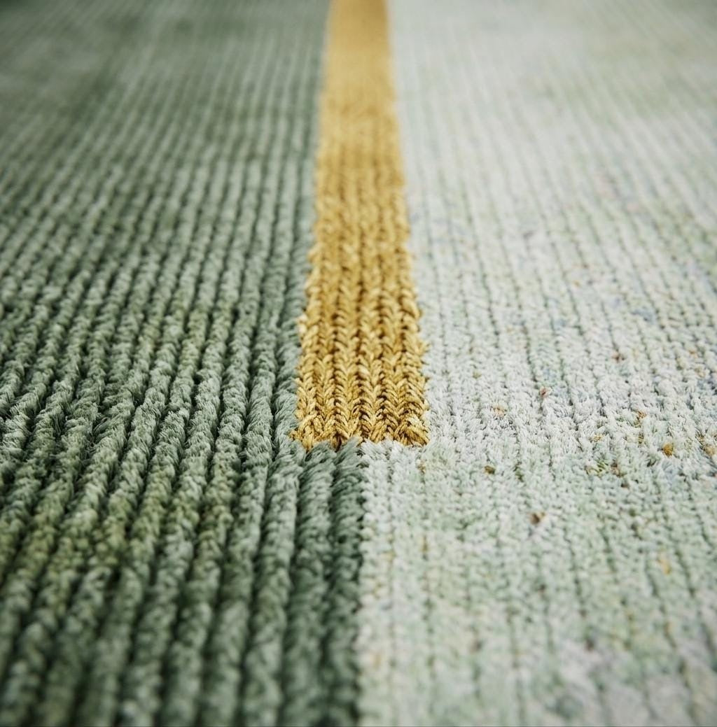 Gros plan sur la texture bouclée de laine et soie de bambou, aux motifs vert et or en relief