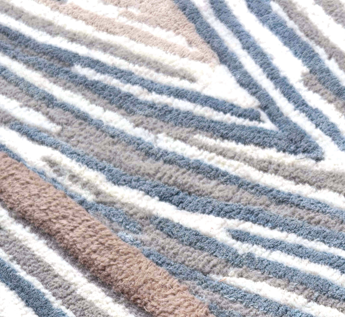 Gros plan sur les textures de laine et viscose, révélant le relief des motifs bleu acier, crème et brun