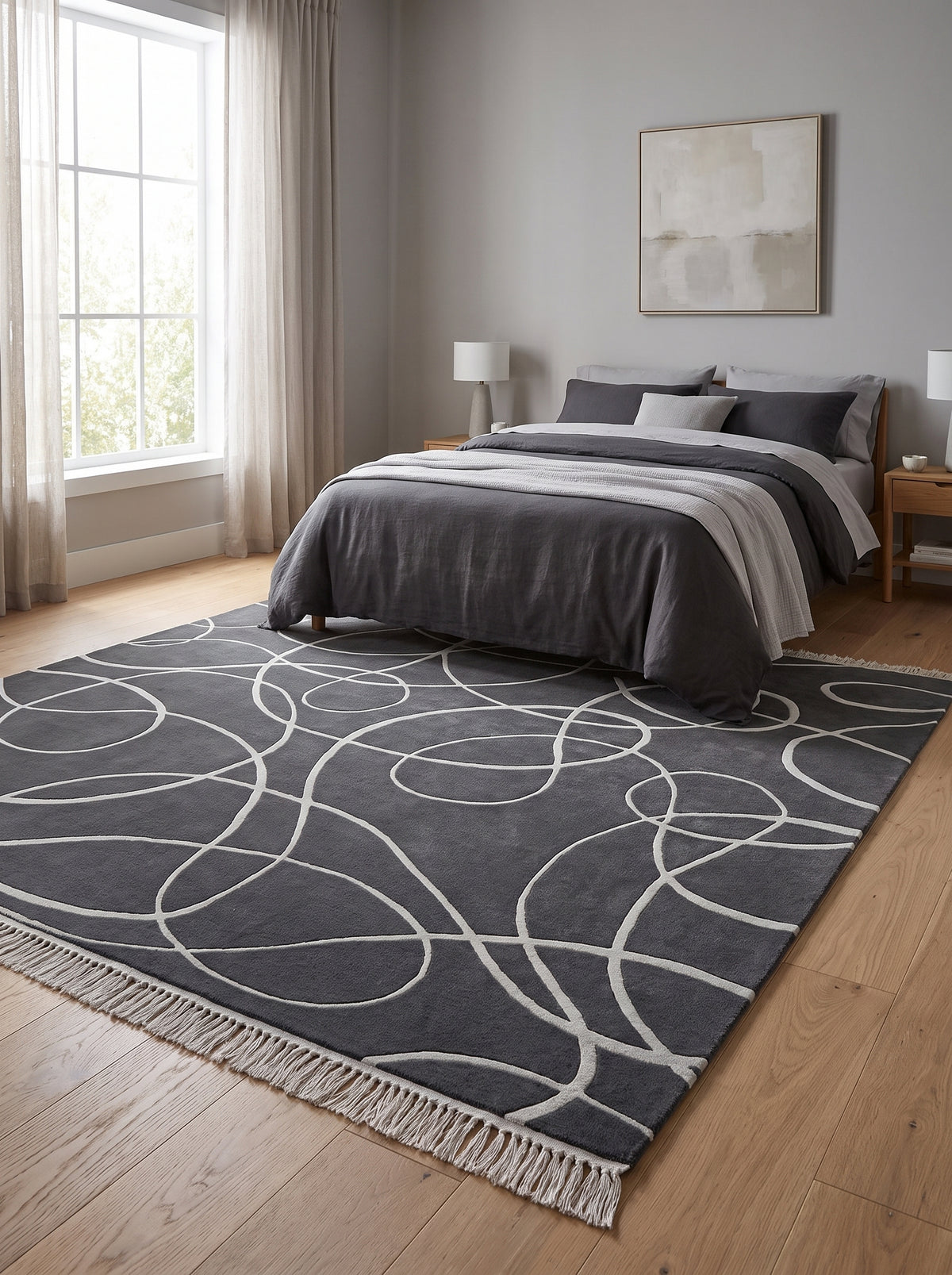 Courbes argentées sculptées animent un tapis en laine et viscose gris anthracite, à franges, dans une chambre