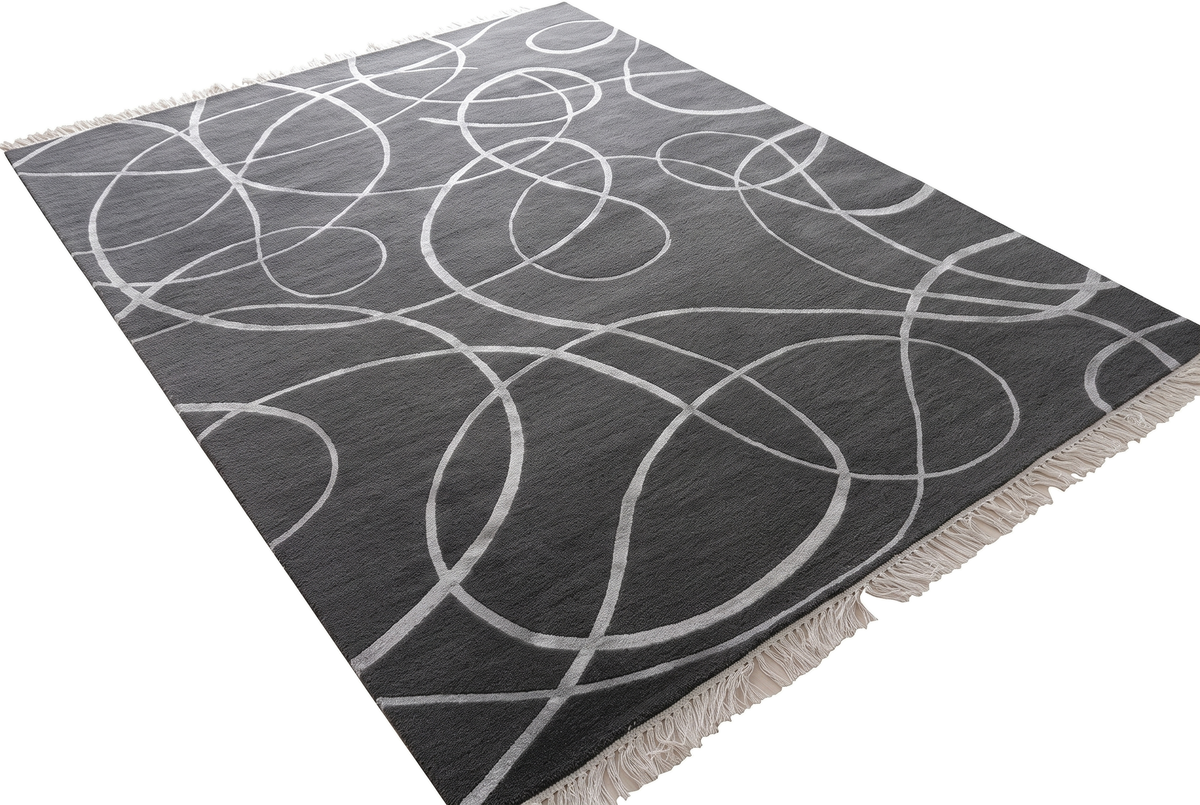 Le relief du tapis laine et viscose anthracite met en valeur les courbes argentées sculptées et les franges claires