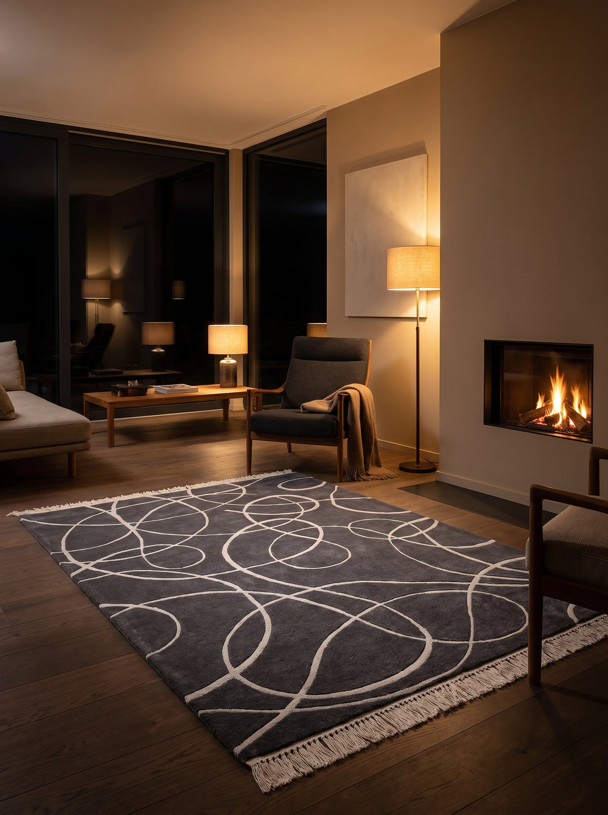 Tapis en laine et viscose gris anthracite, orné de courbes argentées sculptées et de franges claires, dans un salon