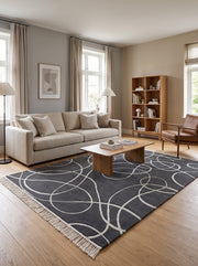 Laine et viscose gris anthracite : tapis tufté main aux courbes argentées sculptées et franges claires, dans un salon