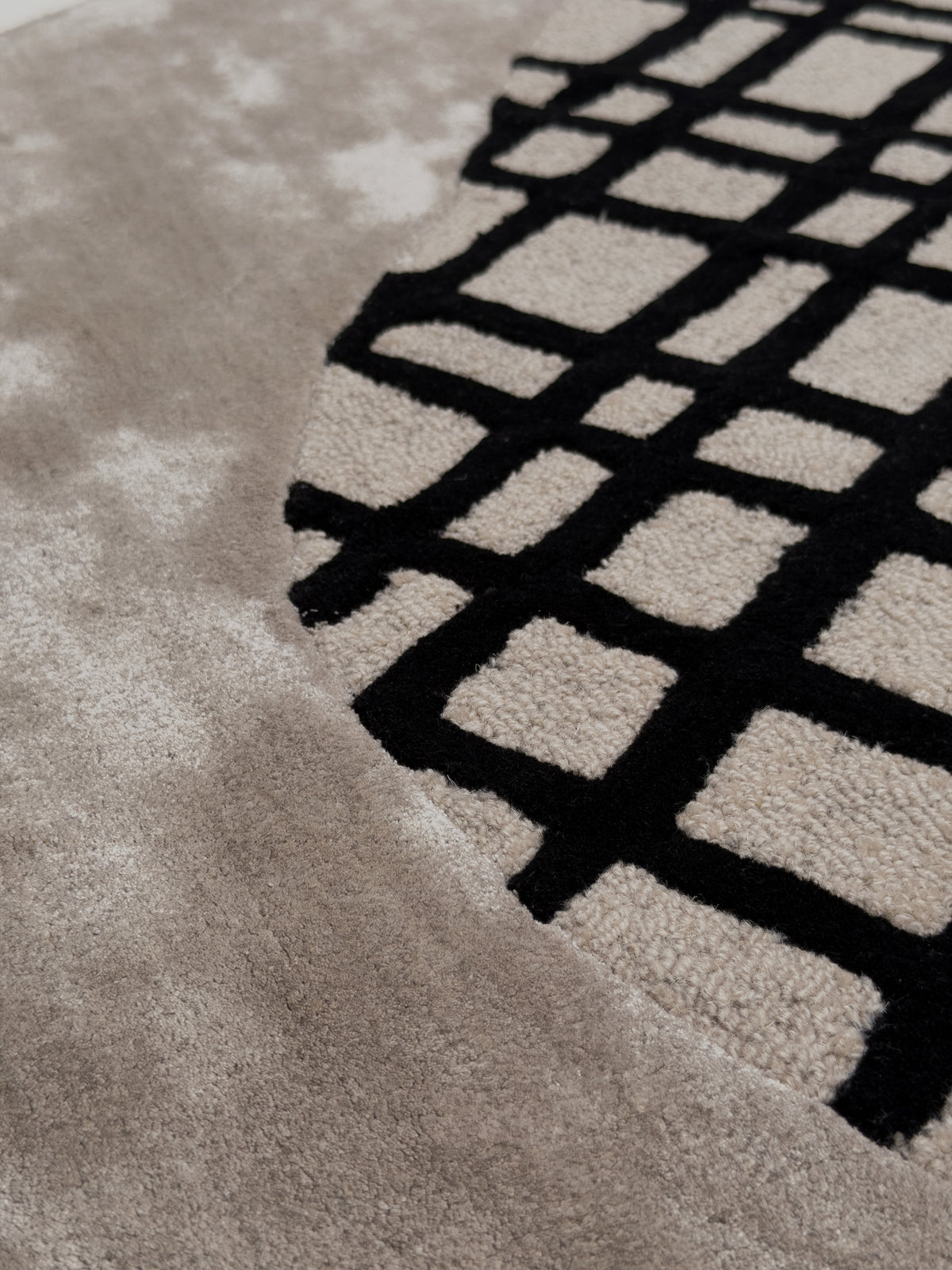 Laine et viscose créent un jeu de matières et de relief avec velours rasé gris et bouclettes taupe à motif noir