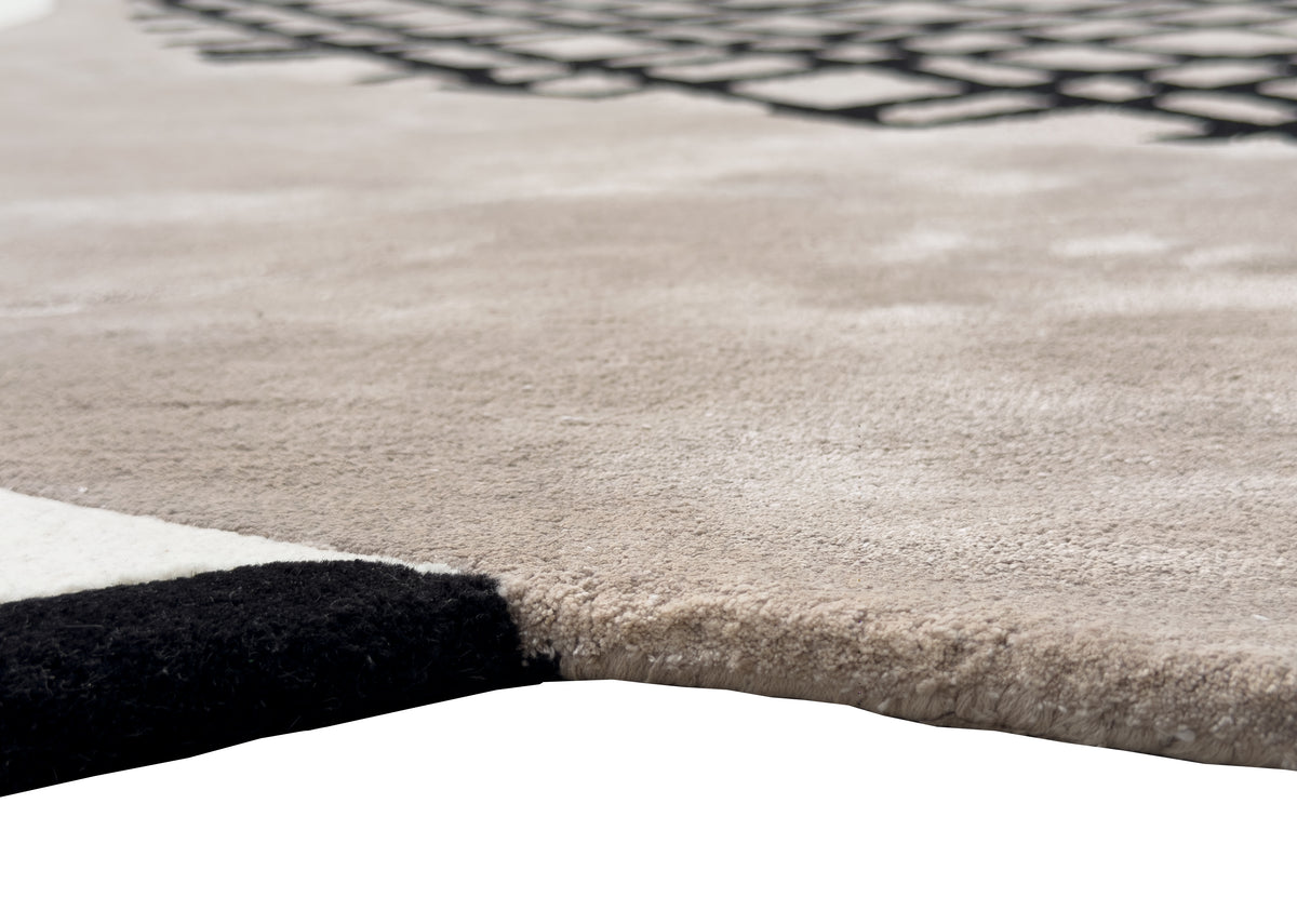 Les bouclettes noires et le velours rasé gris taupe composent ce tapis fait main, offrant un relief contrasté
