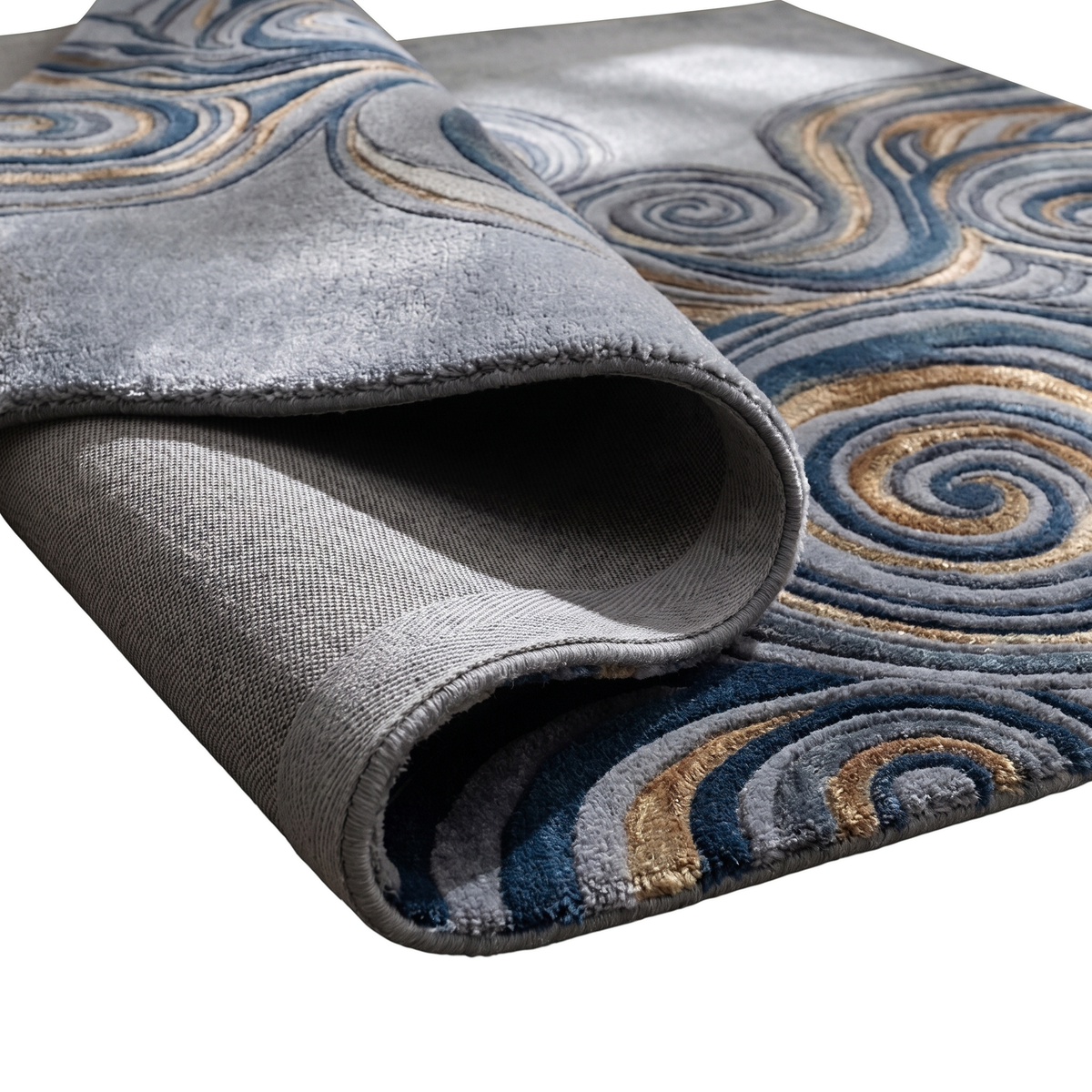 Gros plan sur les spirales sculptées bleu marine, gris et or du tapis gris perle, montrant son envers et son épaisseur