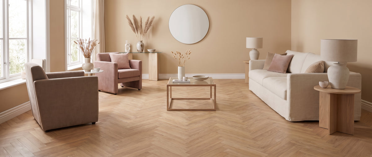 Un salon lumineux avec parquet clair en point de Hongrie, sol nu, meublé de canapé, fauteuils et déco minimaliste