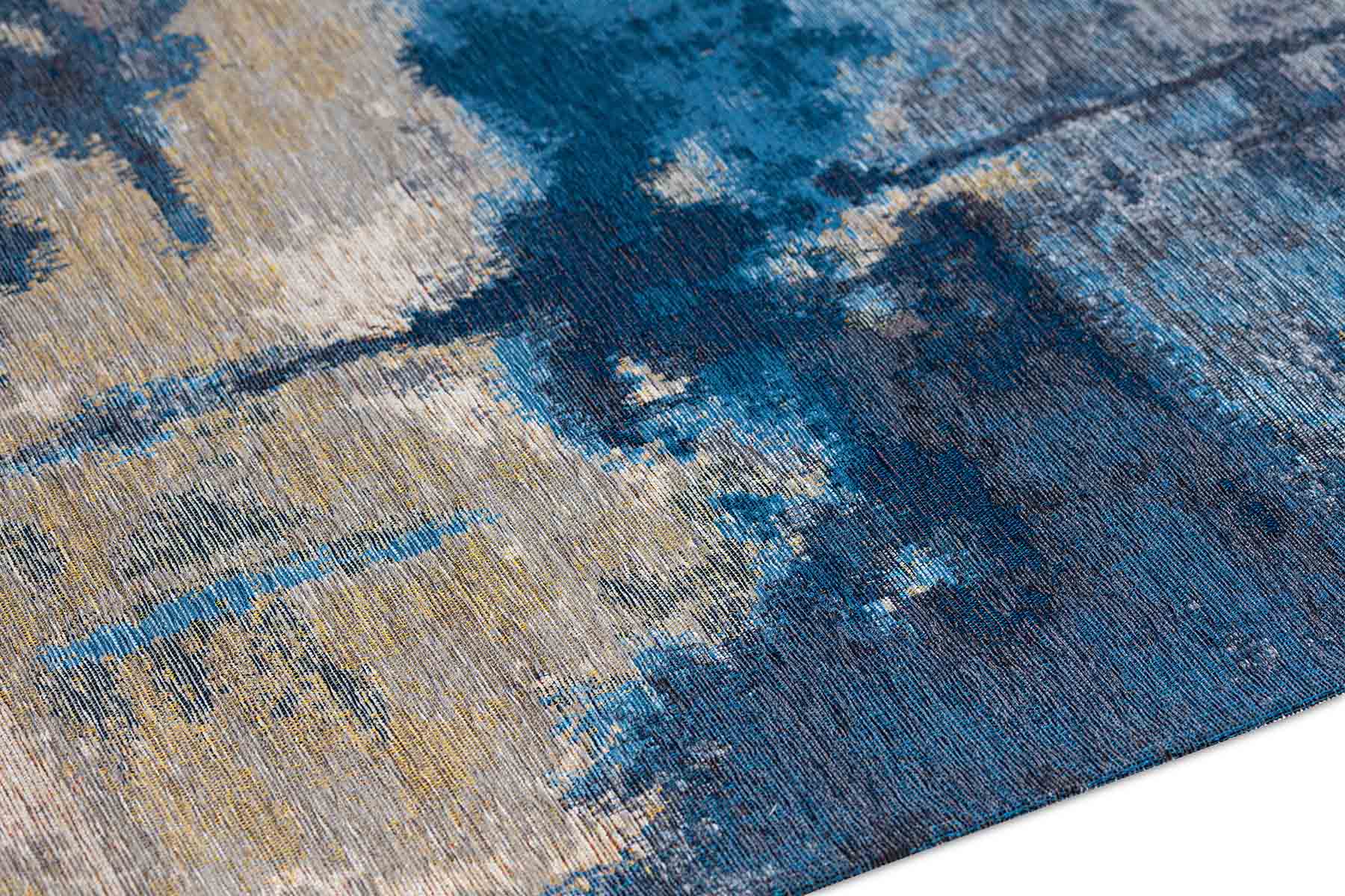 Zoom sur un tapis abstrait aux couleurs bleues et beiges, dévoilant des motifs texturés et des fibres.