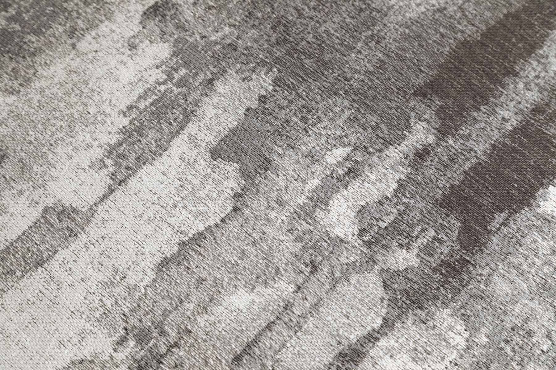 Gros plan sur un tapis lavable gris abstrait Fresko, avec des fibres texturées et un motif de taches irrégulières pour un look contemporain.