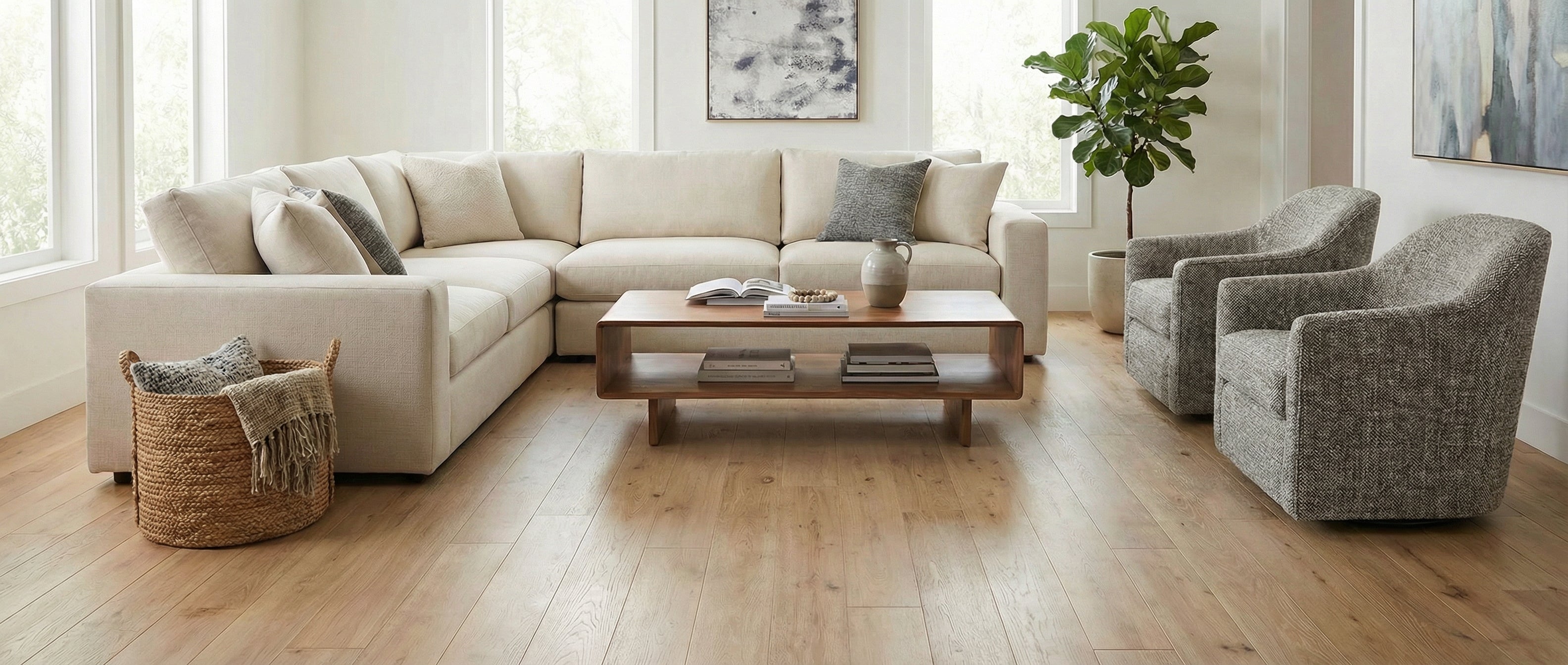 Pièce lumineuse avec canapé crème, fauteuils gris, parquet clair. Espace vide pour un tapis rectangulaire, ambiance