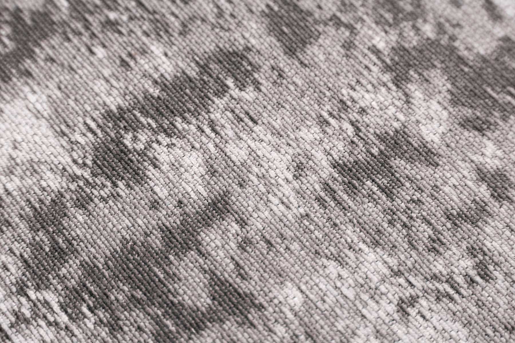 Zoom sur la texture d'un tapis abstrait lavable gris Miro, révélant des fibres subtiles et un motif nuancé.