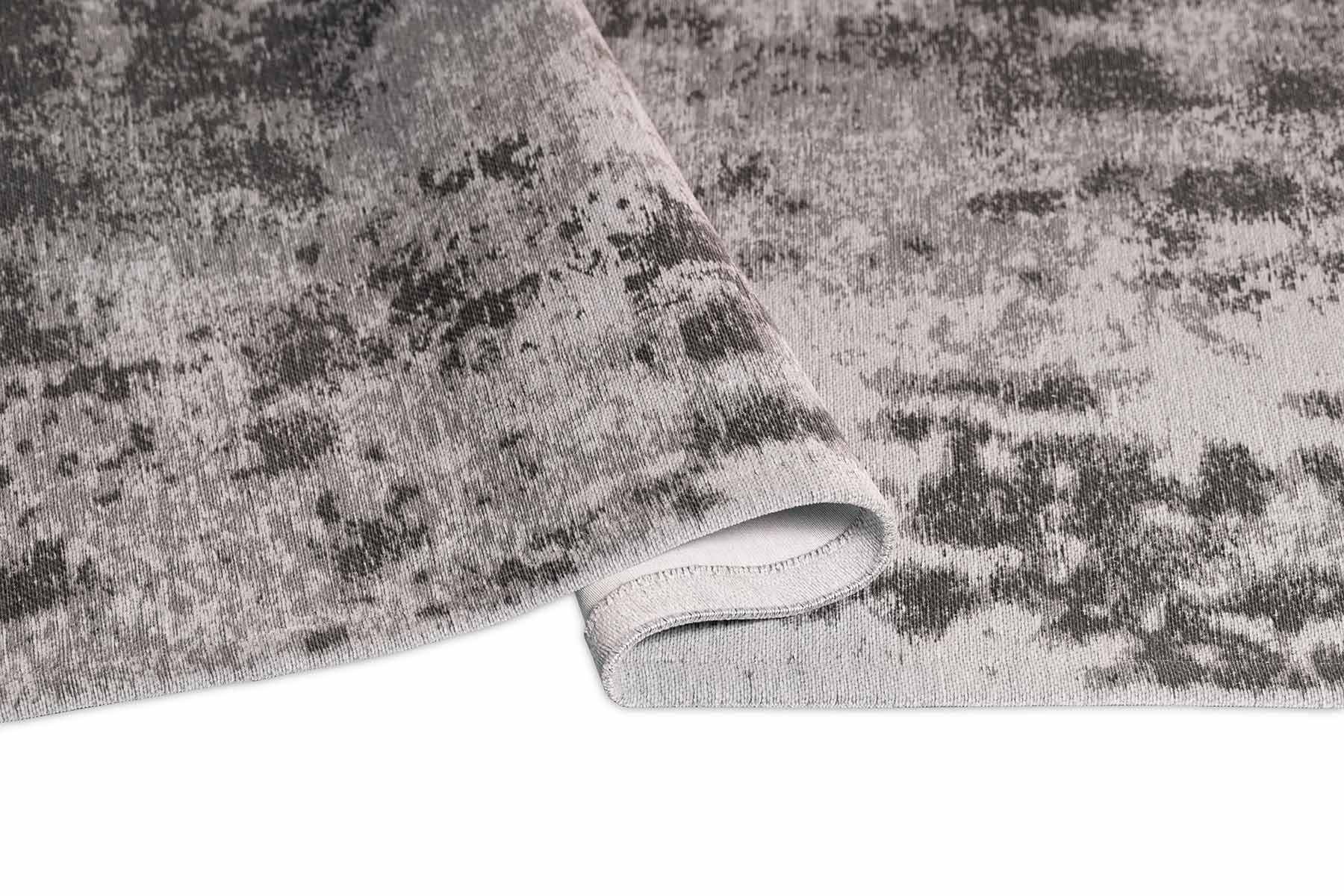 Tapis rectangulaire gris, densité moyenne. Apparence moelleuse, confort apparent. Ambiance sobre