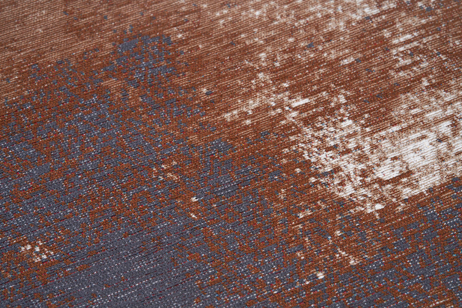 Gros plan sur la texture d'un tapis lavable abstrait aux couleurs terracotta et grise, avec des motifs et un aspect vieilli.