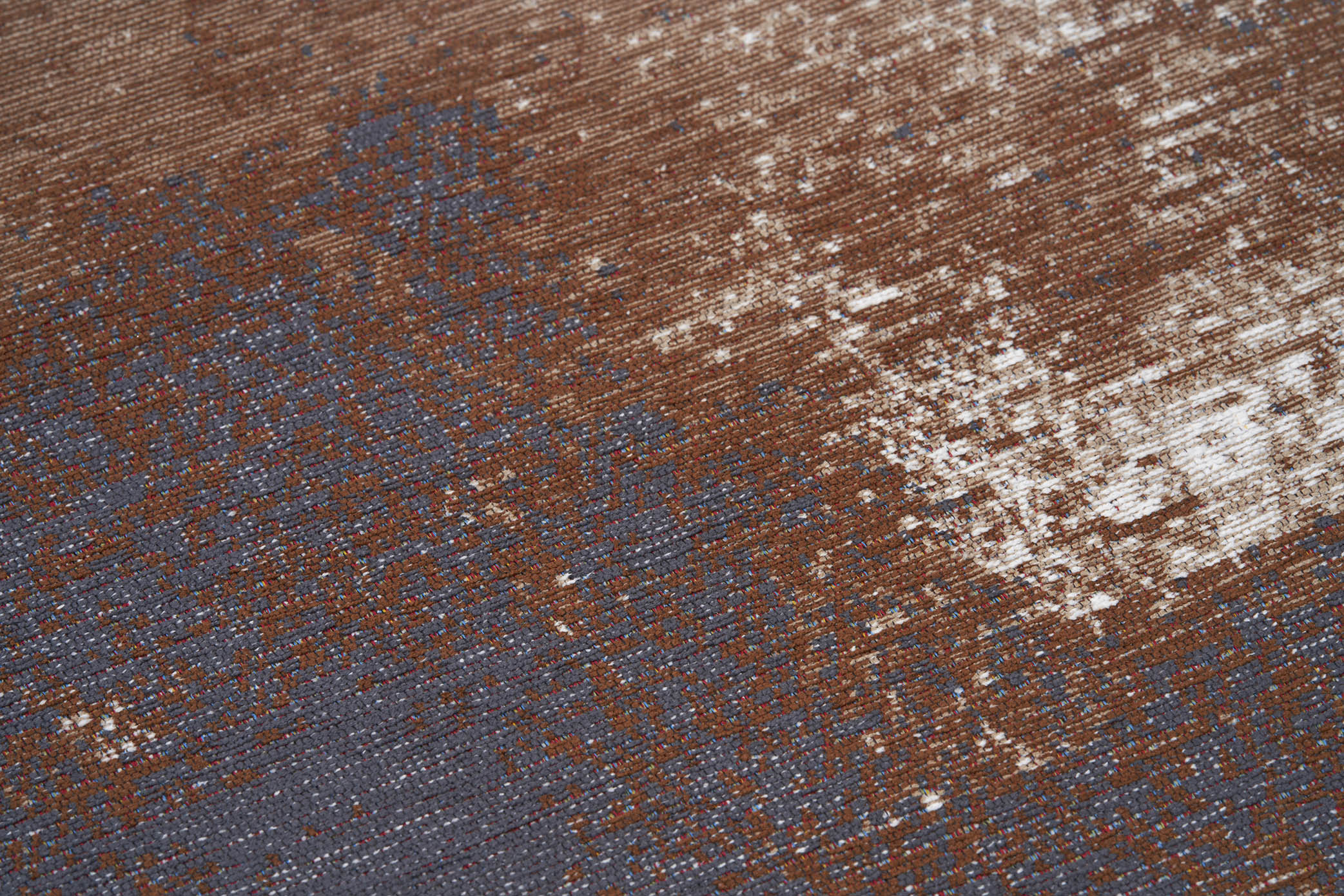 Gros plan sur la texture d'un tapis lavable abstrait aux couleurs terracotta et grise, avec des motifs et un aspect vieilli.