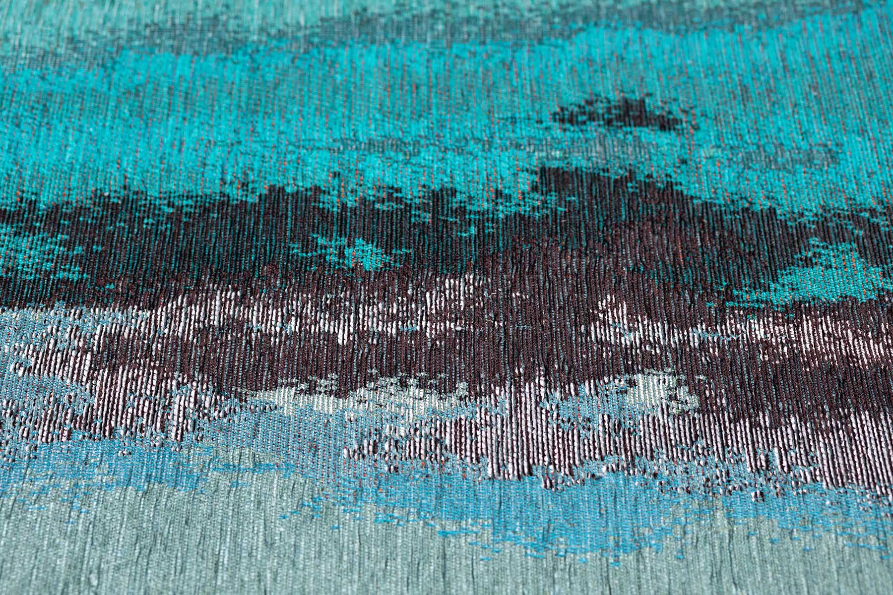 Gros plan sur un tapis turquoise abstrait avec des fibres texturées, parfait pour ajouter une touche moderne et artistique à votre intérieur.