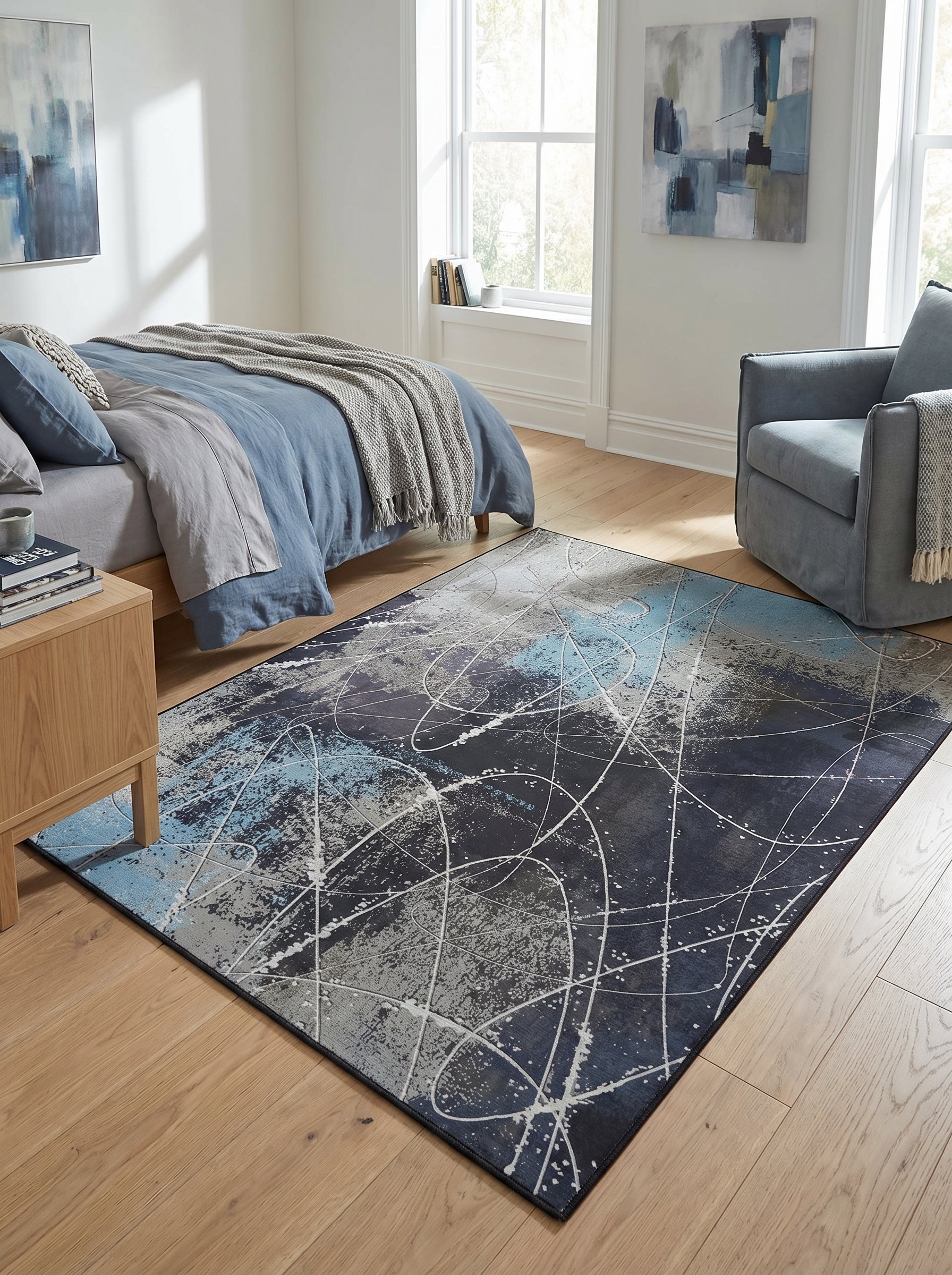Tapis rectangulaire abstrait bleu marine, gris et bleu ciel, avec des motifs d'éclaboussures et de lignes courbes blanches, dans une chambre moderne