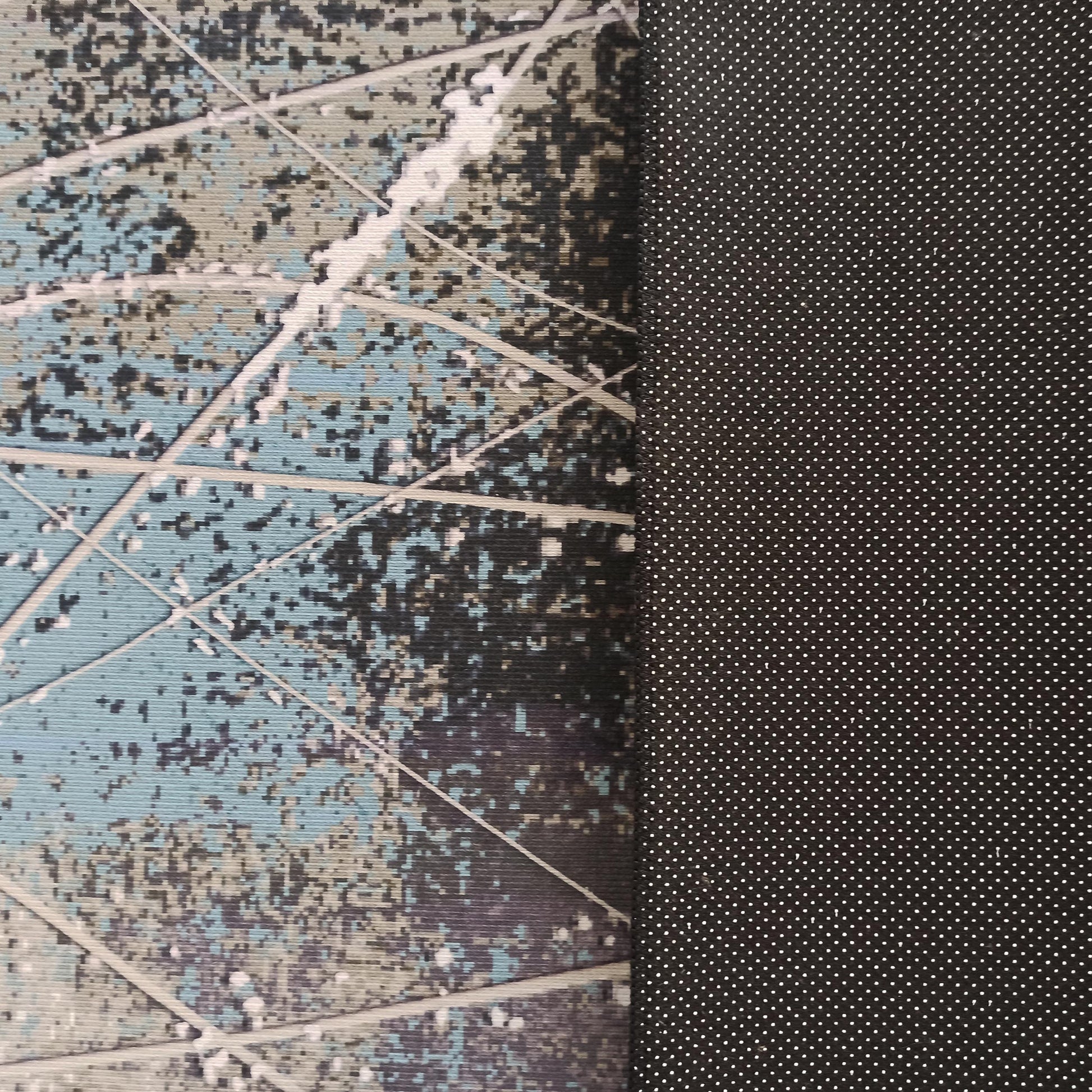 Tapis avec un motif abstrait bleu clair, gris, noir et blanc, et un envers noir antidérapant parsemé de petits pois blancs
