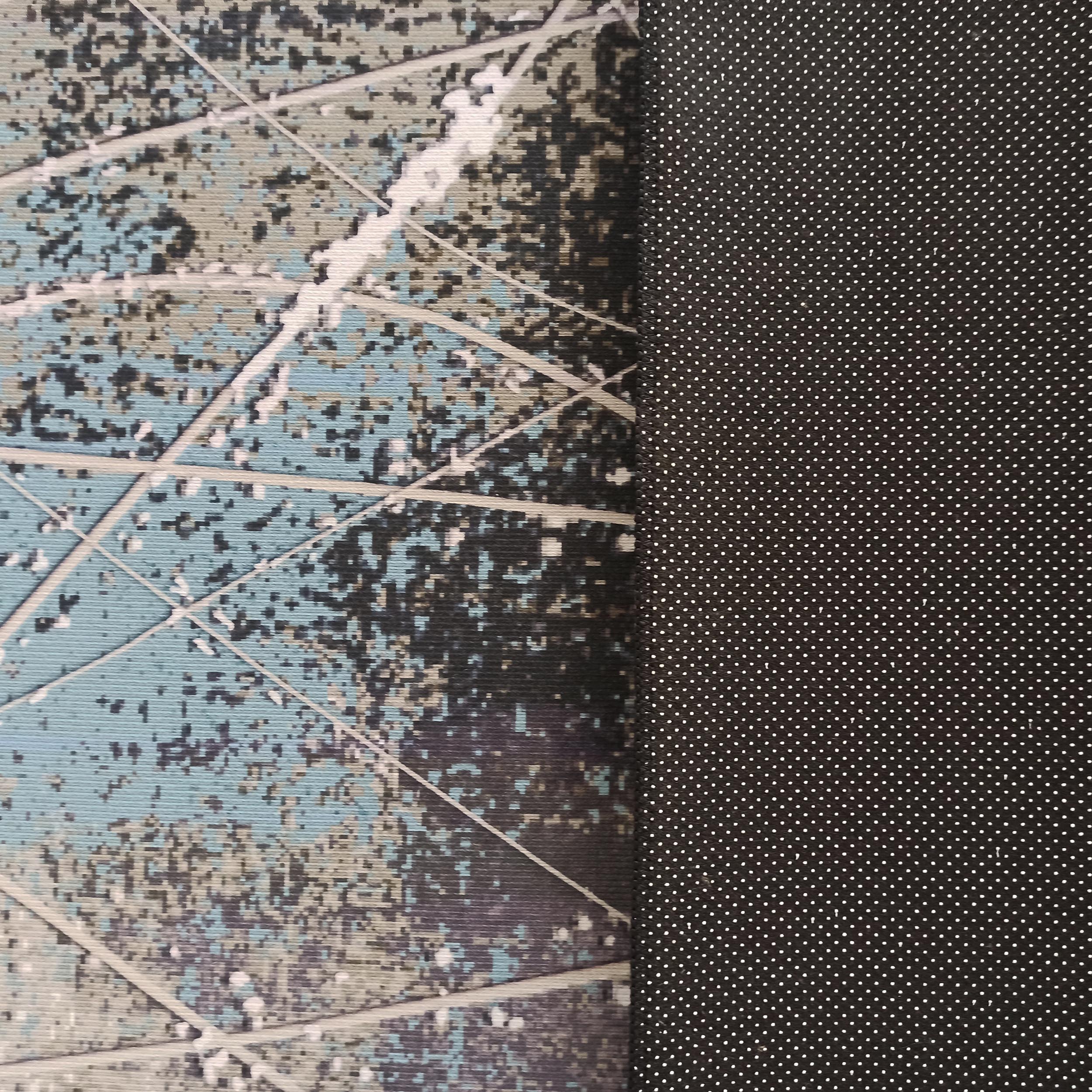 Tapis avec un motif abstrait bleu clair, gris, noir et blanc, et un envers noir antidérapant parsemé de petits pois blancs