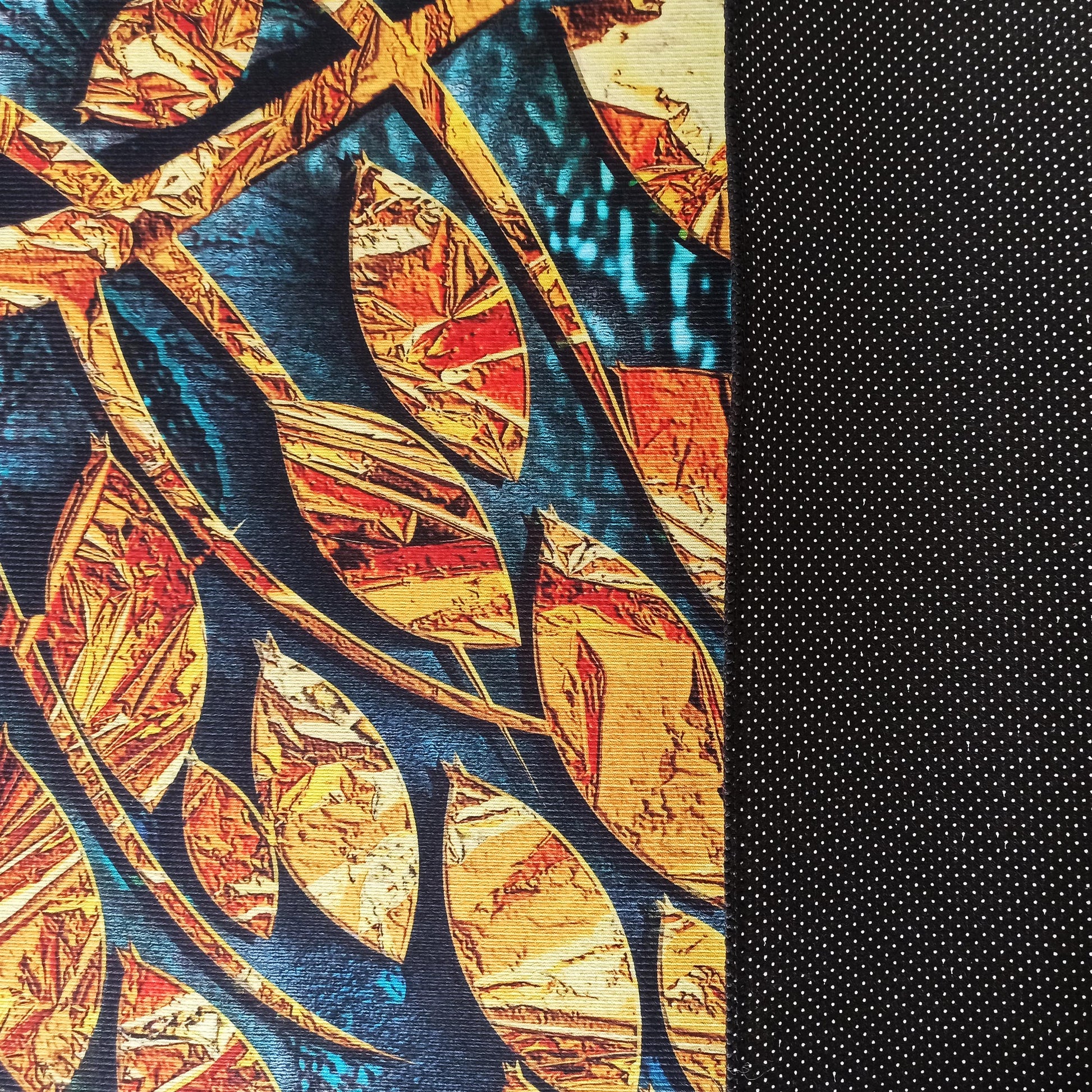 Tapis texturé avec des feuilles stylisées orange, jaune et rouge sur fond bleu-vert, et une face arrière noire à pois blancs