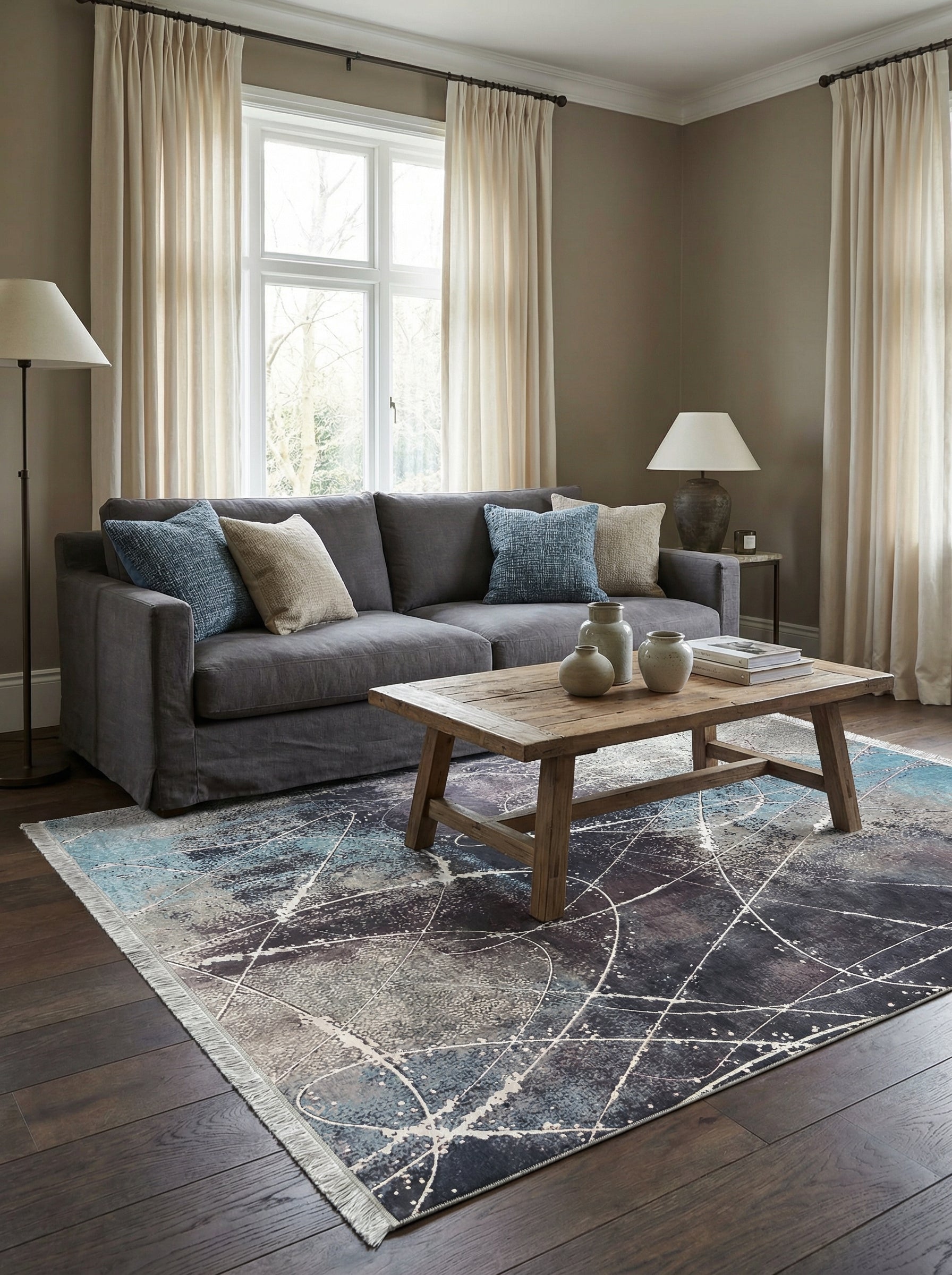 Tapis rectangulaire abstrait aux motifs de taches claires et de lignes blanches sur fond bleu marine et gris, avec des franges, dans un salon