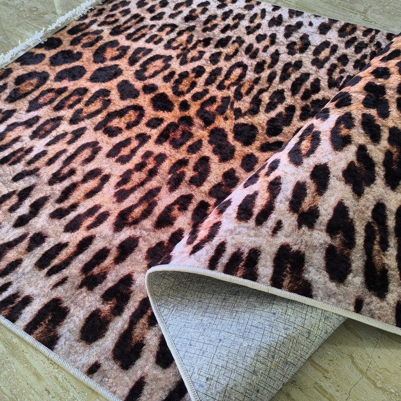 Tapis moelleux à motif léopard marron, noir et beige clair. Son envers gris texturé est visible sur une partie repliée