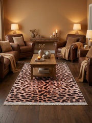 Tapis rectangulaire à motif léopard avec des taches noires et marron sur fond ocre rosé, bordé de franges claires, dans un salon cosy