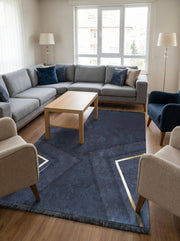 Tapis rectangulaire bleu foncé texturé avec motifs géométriques dorés et franges, au centre d'un salon