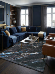 Tapis rectangulaire noir marbré de veines bleues, blanches et dorées, bordé de franges grises, dans un salon élégant