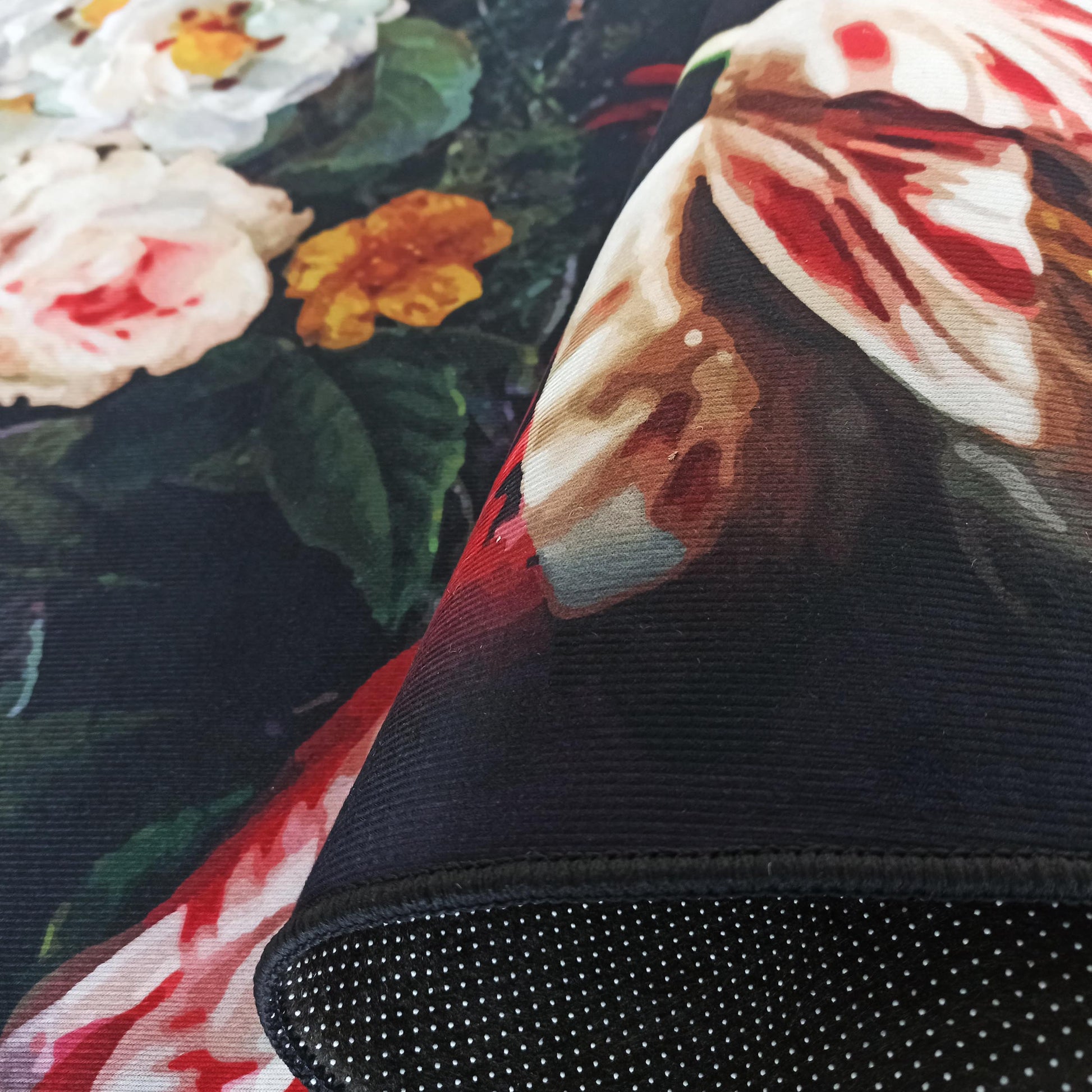 Tapis floral aux motifs de roses blanches, roses et oranges sur fond sombre, avec envers antidérapant à pois