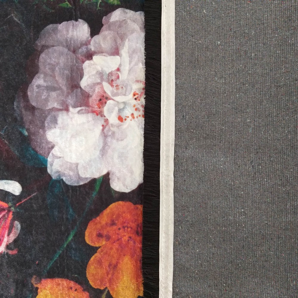 Tapis floral avec de grandes fleurs blanches et oranges sur fond sombre, bordé de franges noires et d'un dos gris uni