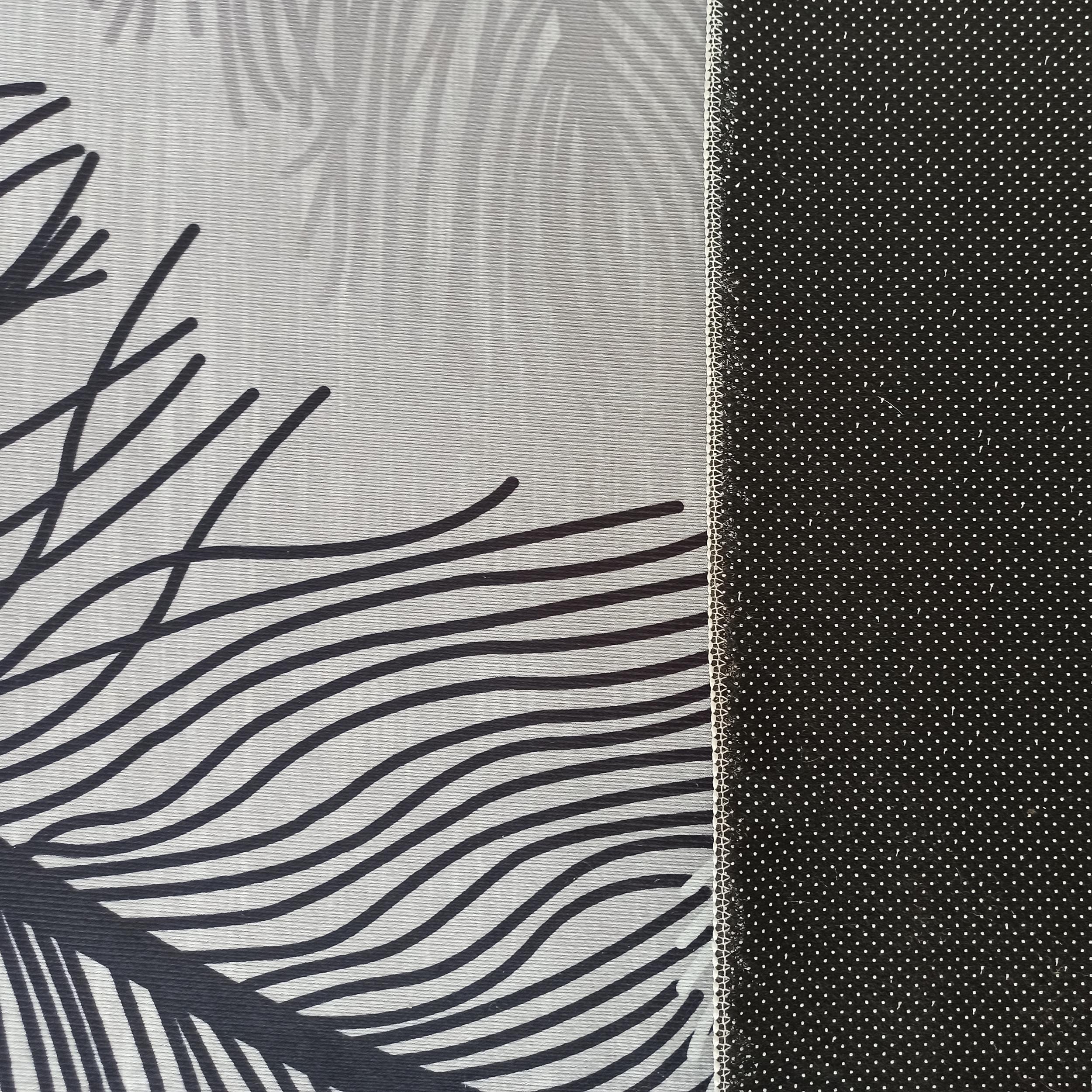 Tapis gris clair à motifs de feuilles stylisées noires et grises, avec une bande latérale antidérapante noire à pois blancs