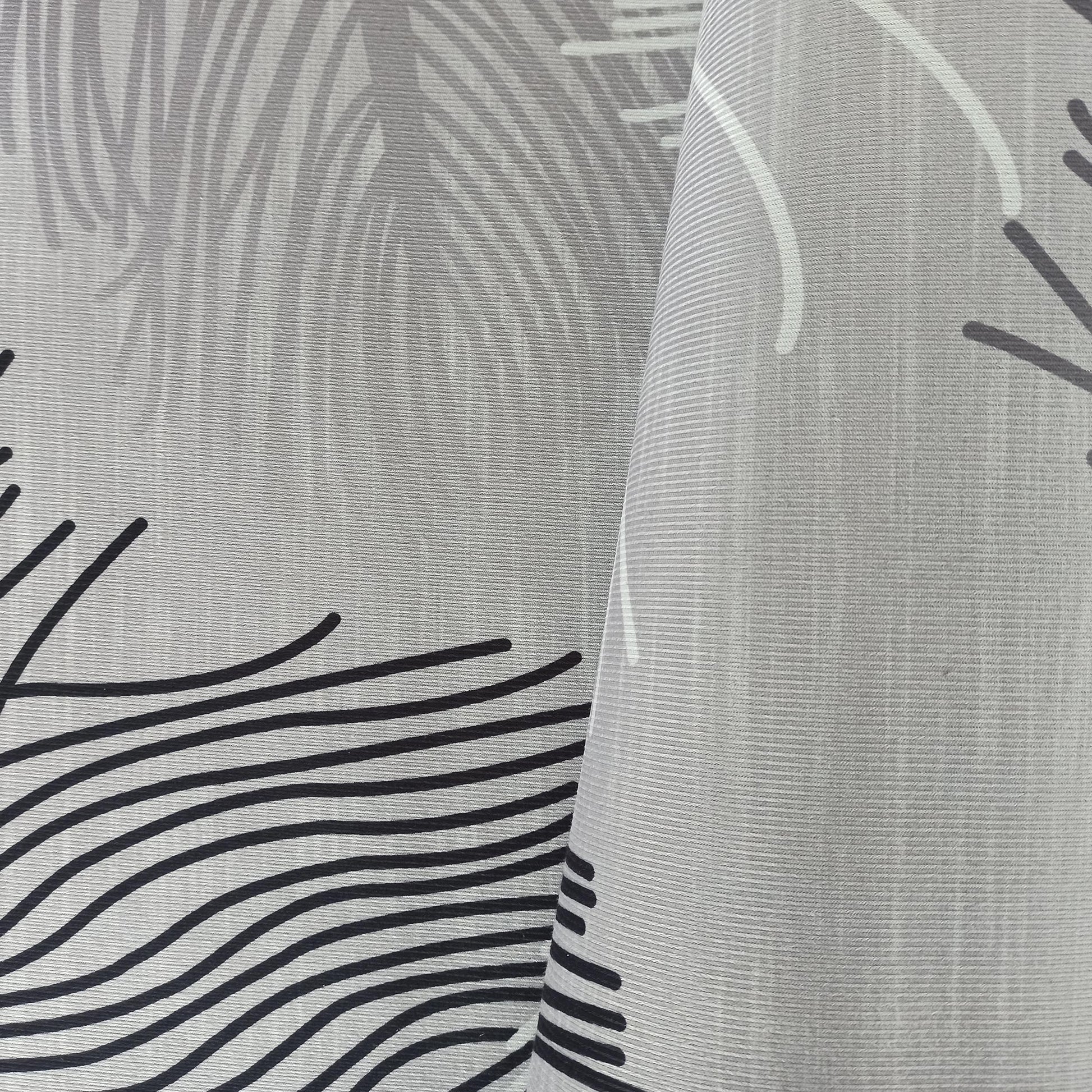 Tapis gris clair à texture striée avec des motifs de feuilles gris pâle et de lignes ondulées noires, une section est repliée