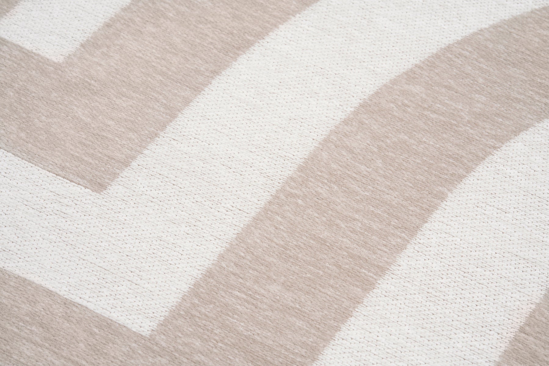 Tapis rectangulaire beige clair. Tissage plat, motifs géométriques en relief. Aspect tactile doux et uniforme
