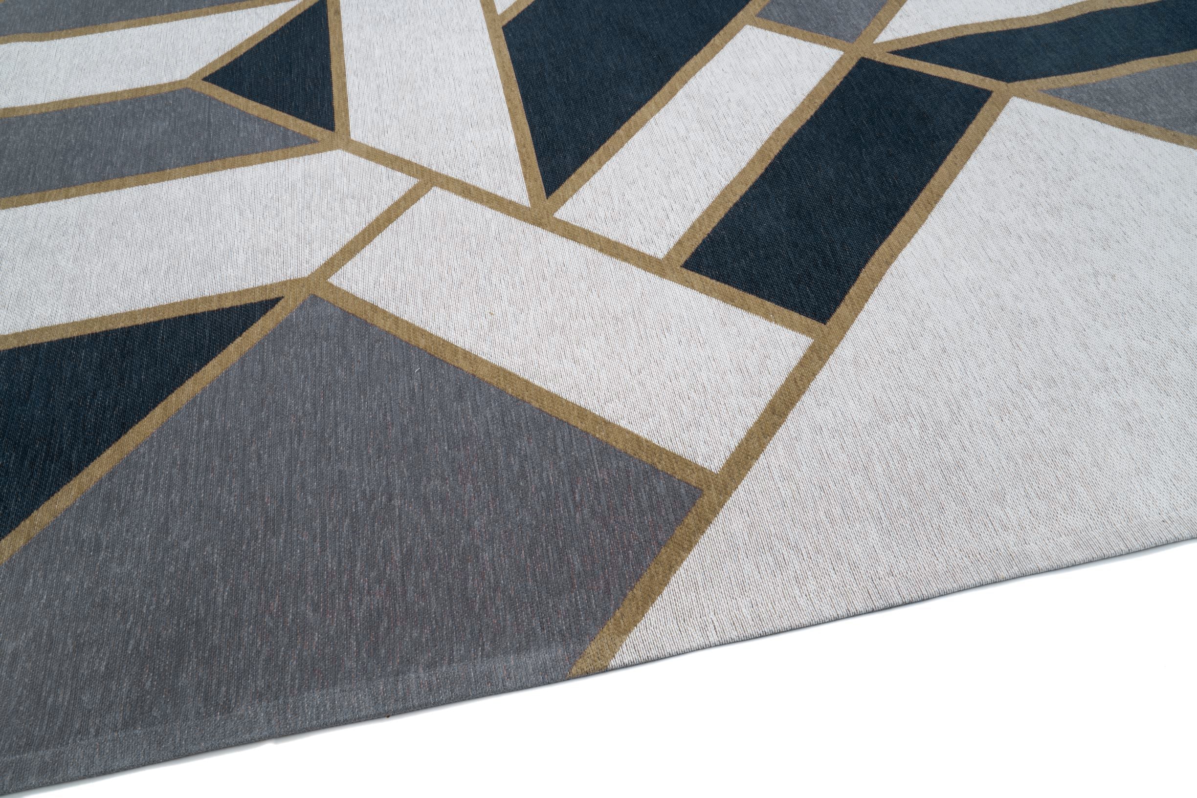 Tapis tissé, texture en relief, aspect tactile. Formes géométriques, couleurs bleu, gris et beige. Ambiance moderne