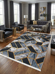 Tapis rectangulaire aux motifs géométriques noirs, gris marbré et or, avec des franges blanches, posé sur un parquet dans un salon