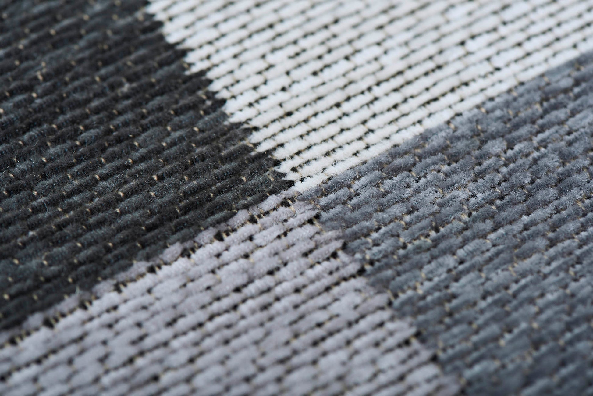 Gros plan d'un tapis rectangulaire. Tissage en relief, aspect tactile. Bordure beige. Couleurs grises