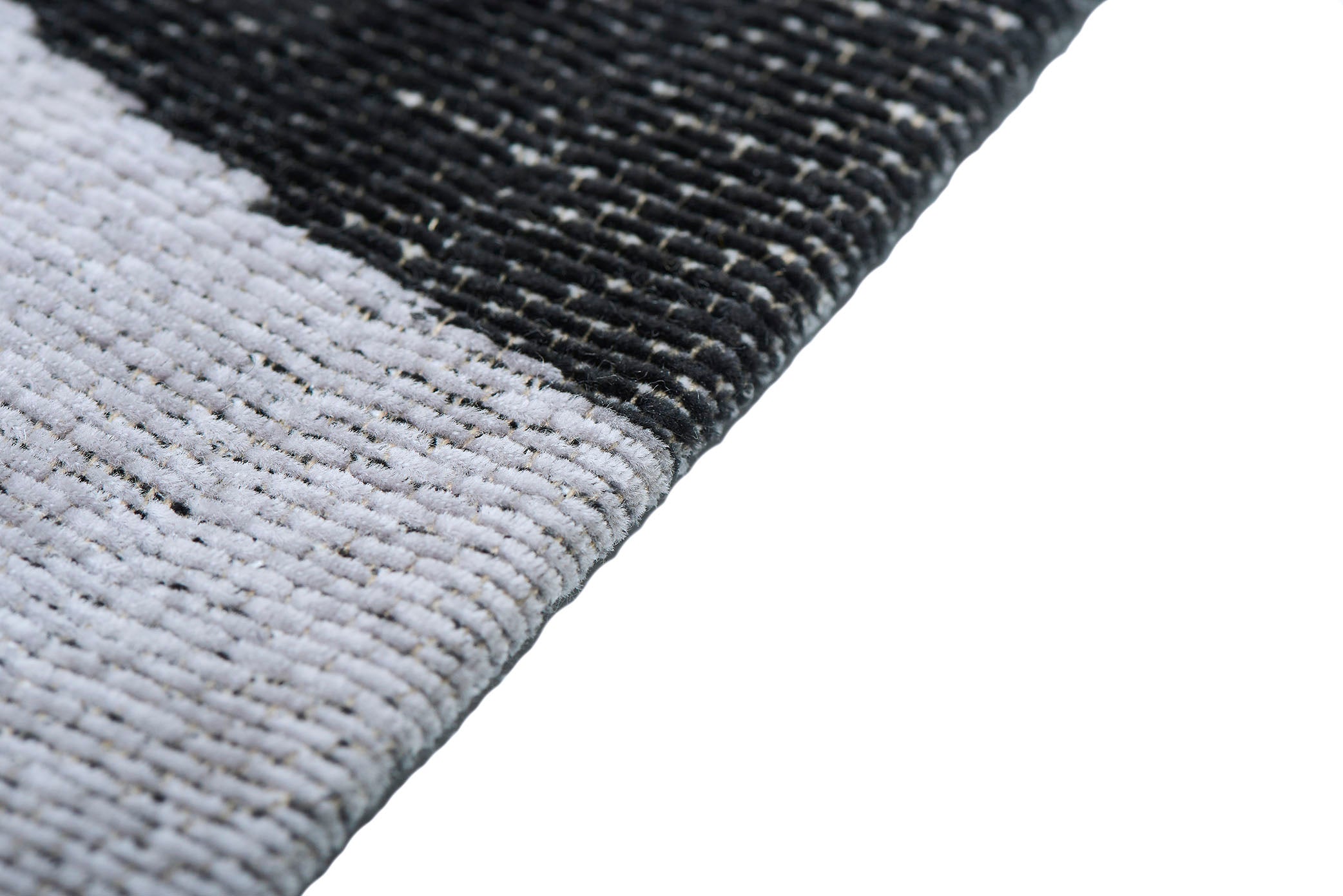 Tapis à poils denses, moelleux, bicolore gris et noir. Confort apparent. Ambiance feutrée